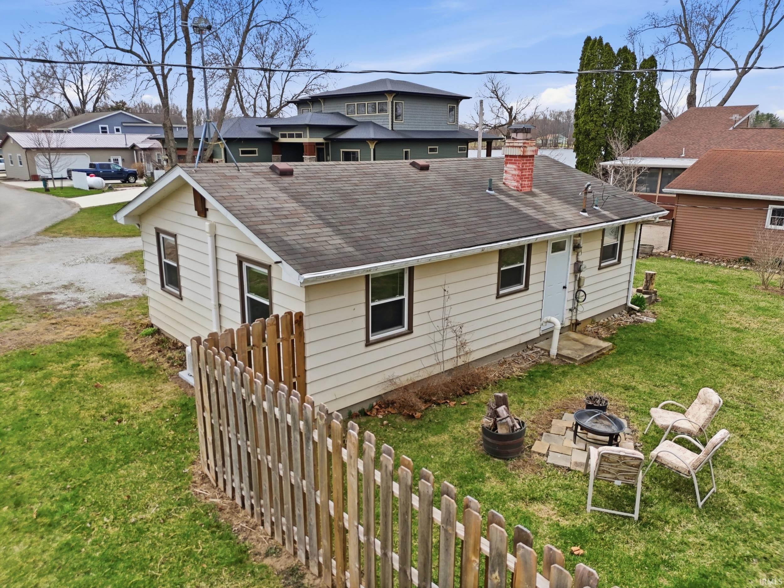 Back of property with an outdoor fire pit, a shingled roof, a chimney, and a residential view