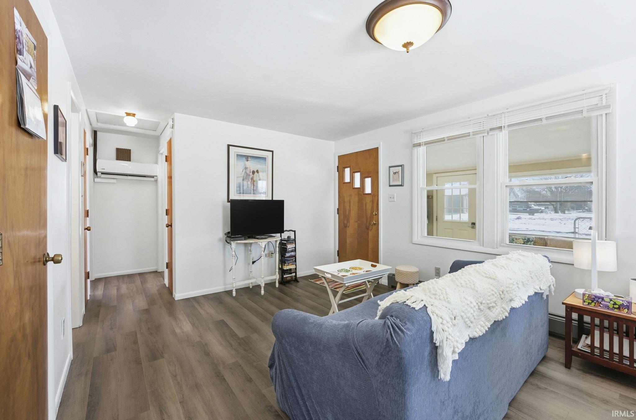 Living room with wood finished floors and a mini split for heating / cooling