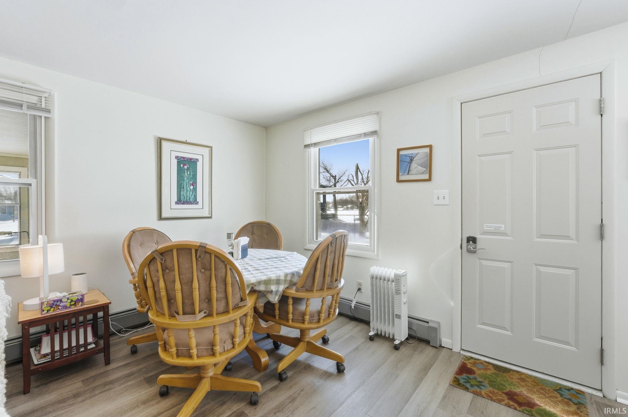 Dining area with light wood-style flooring, baseboard heating, and radiator heating unit