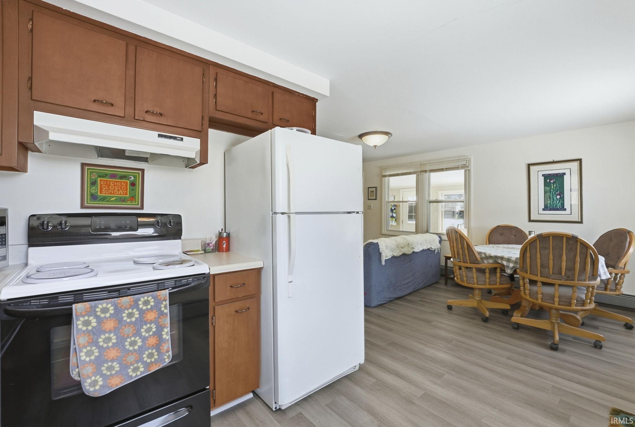 Kitchen featuring range with electric stovetop, freestanding refrigerator, wood finish cabinets, light countertops, and light wood-style floors