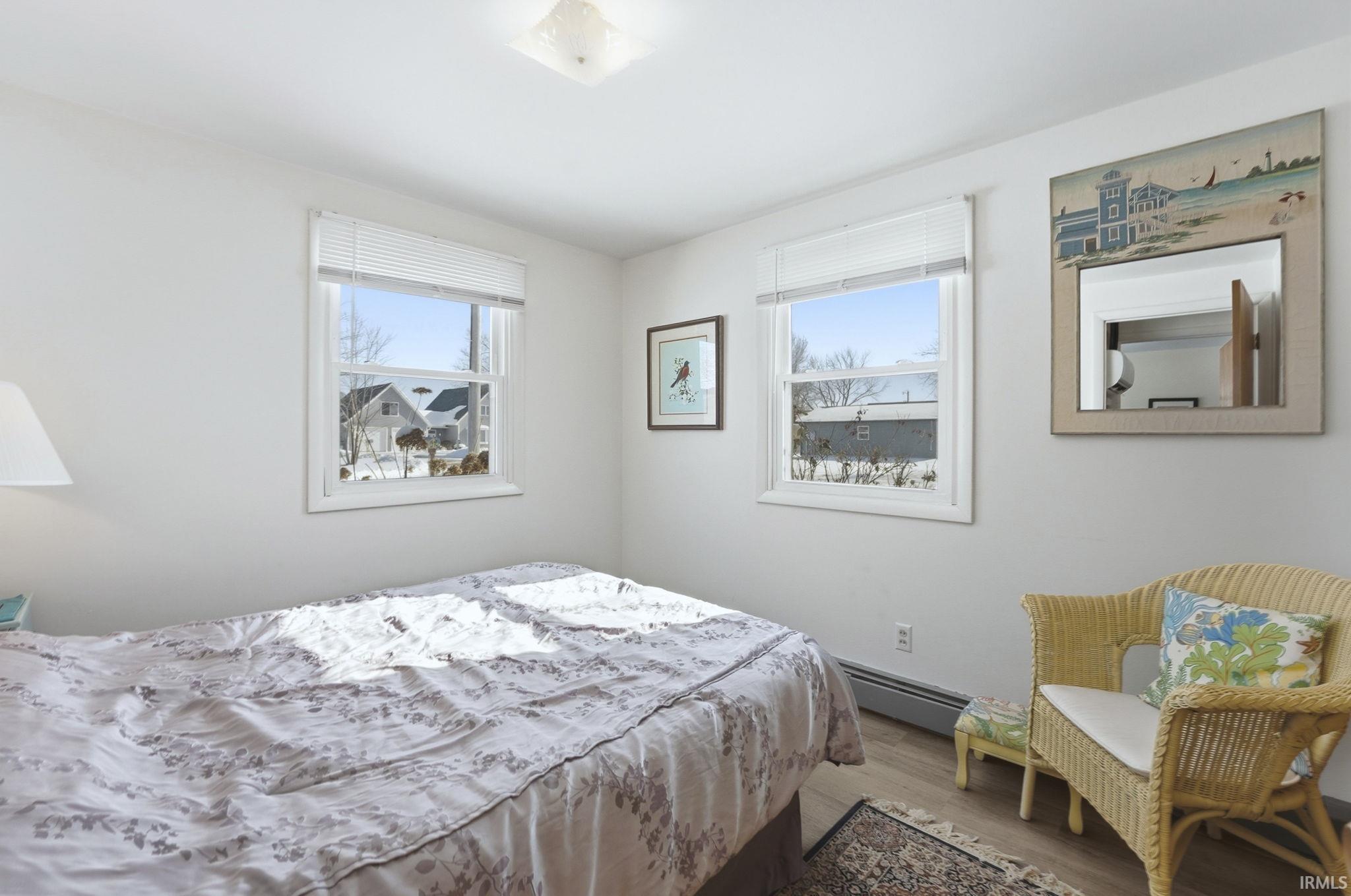 Bedroom with wood finished floors and baseboard heating