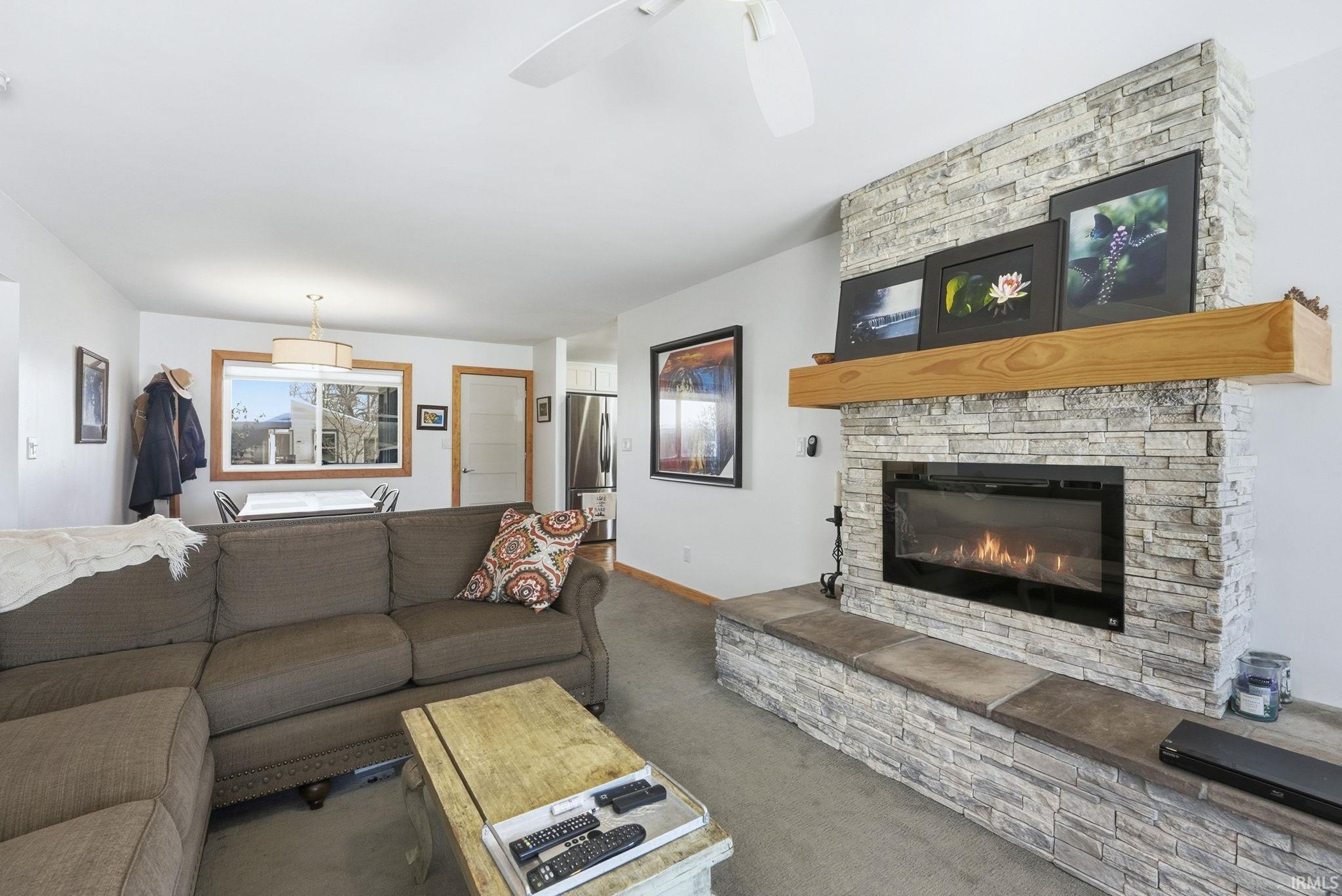 Carpeted living room with a fireplace and ceiling fan
