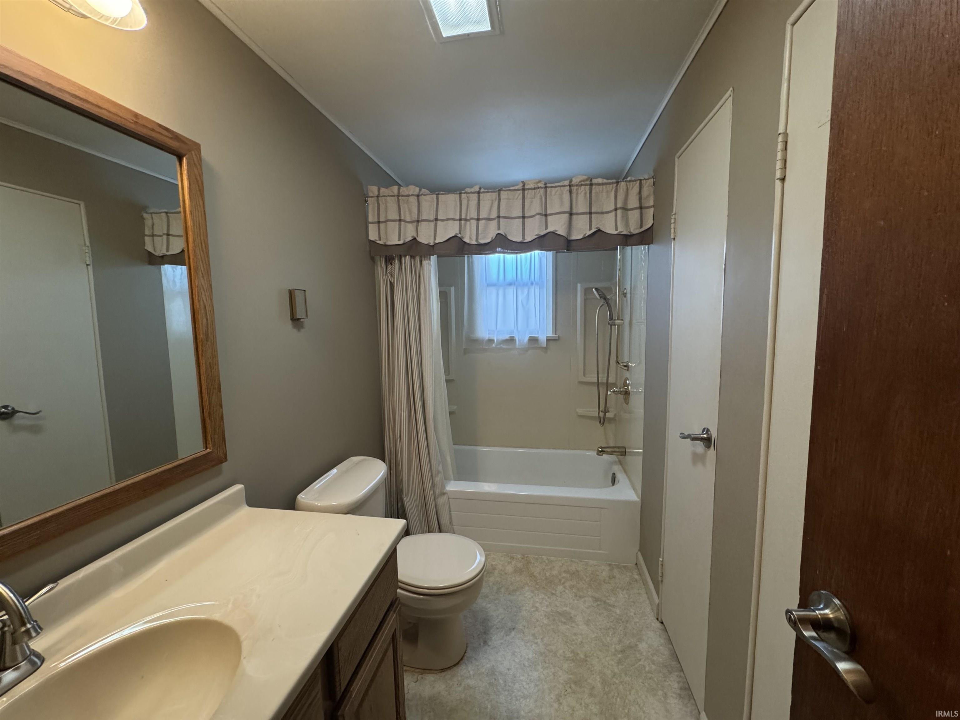 Bathroom with vanity, shower / bathtub combination with curtain, and ornamental molding
