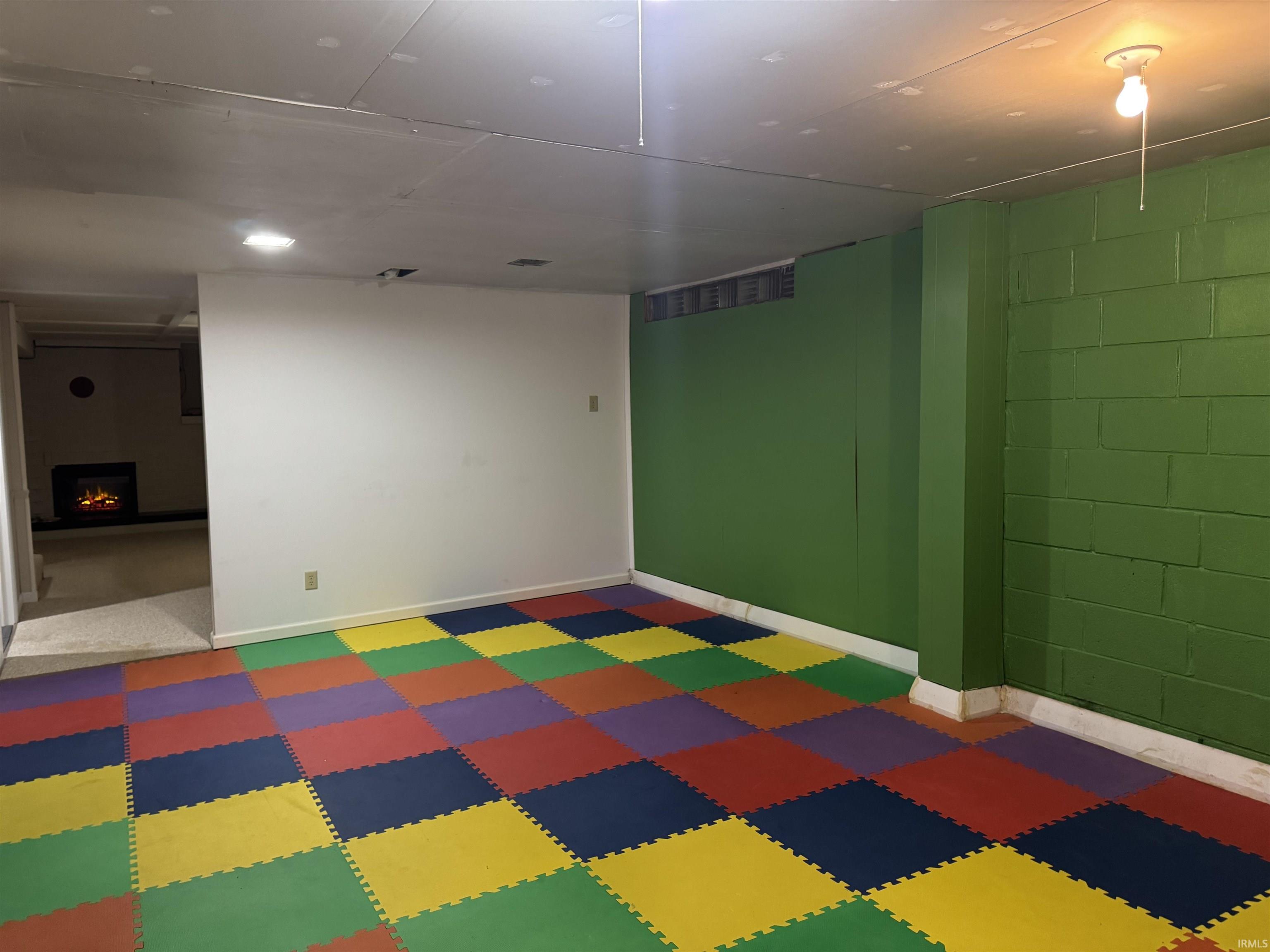 Finished basement featuring concrete block wall and a lit fireplace