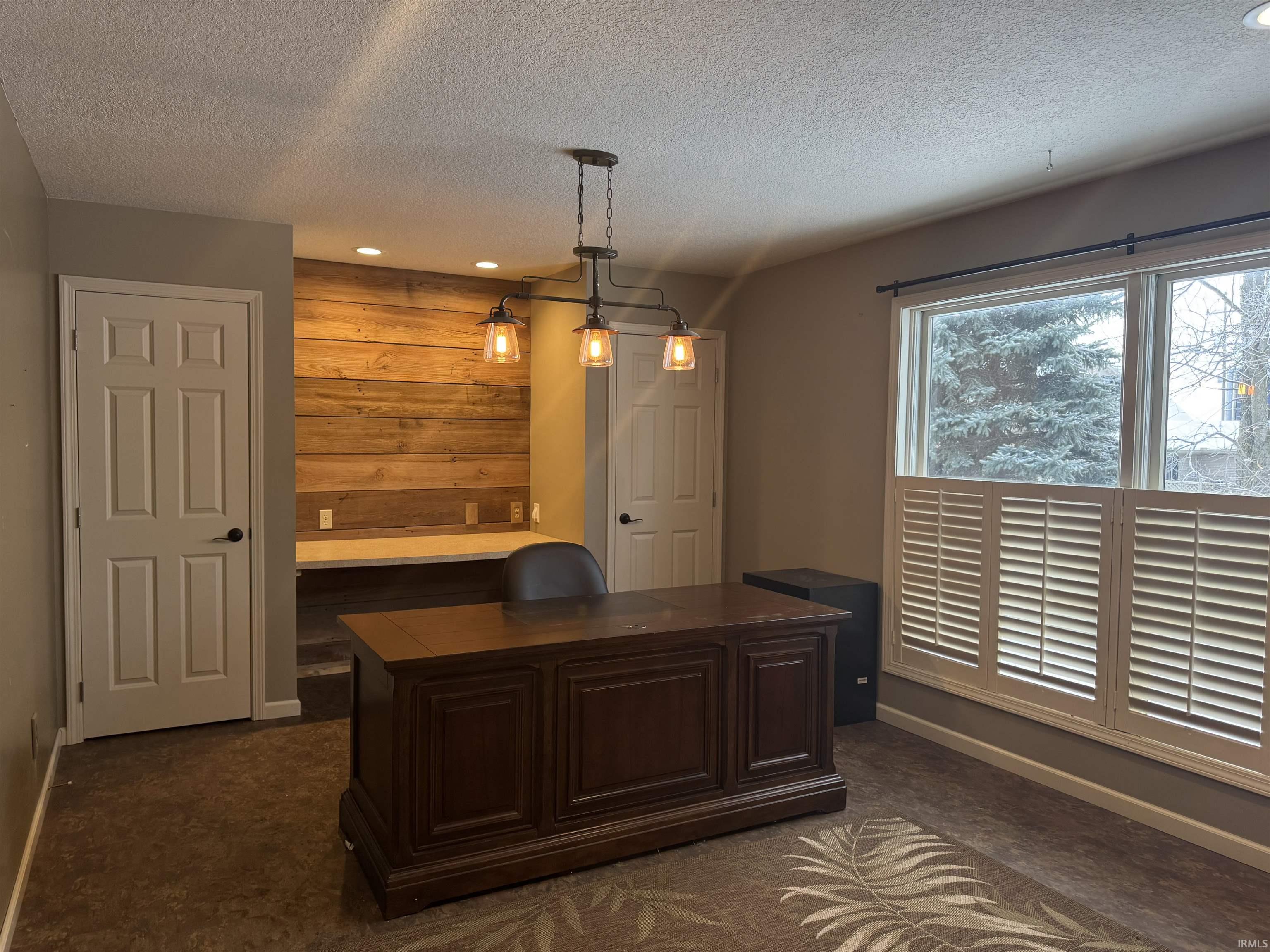 Office featuring recessed lighting, wood walls, and a textured ceiling