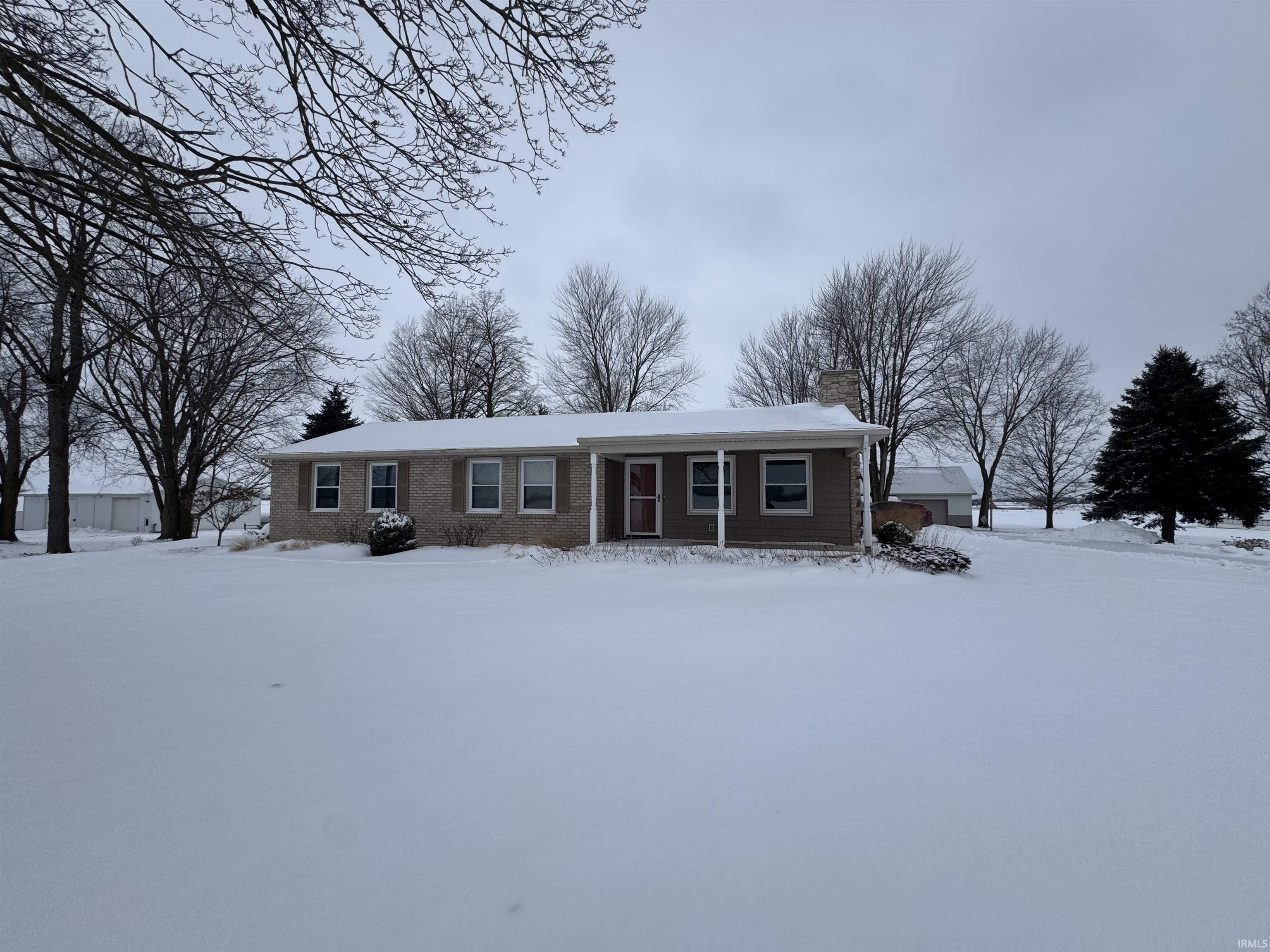 Ranch-style home with a chimney, brick siding, and a porch