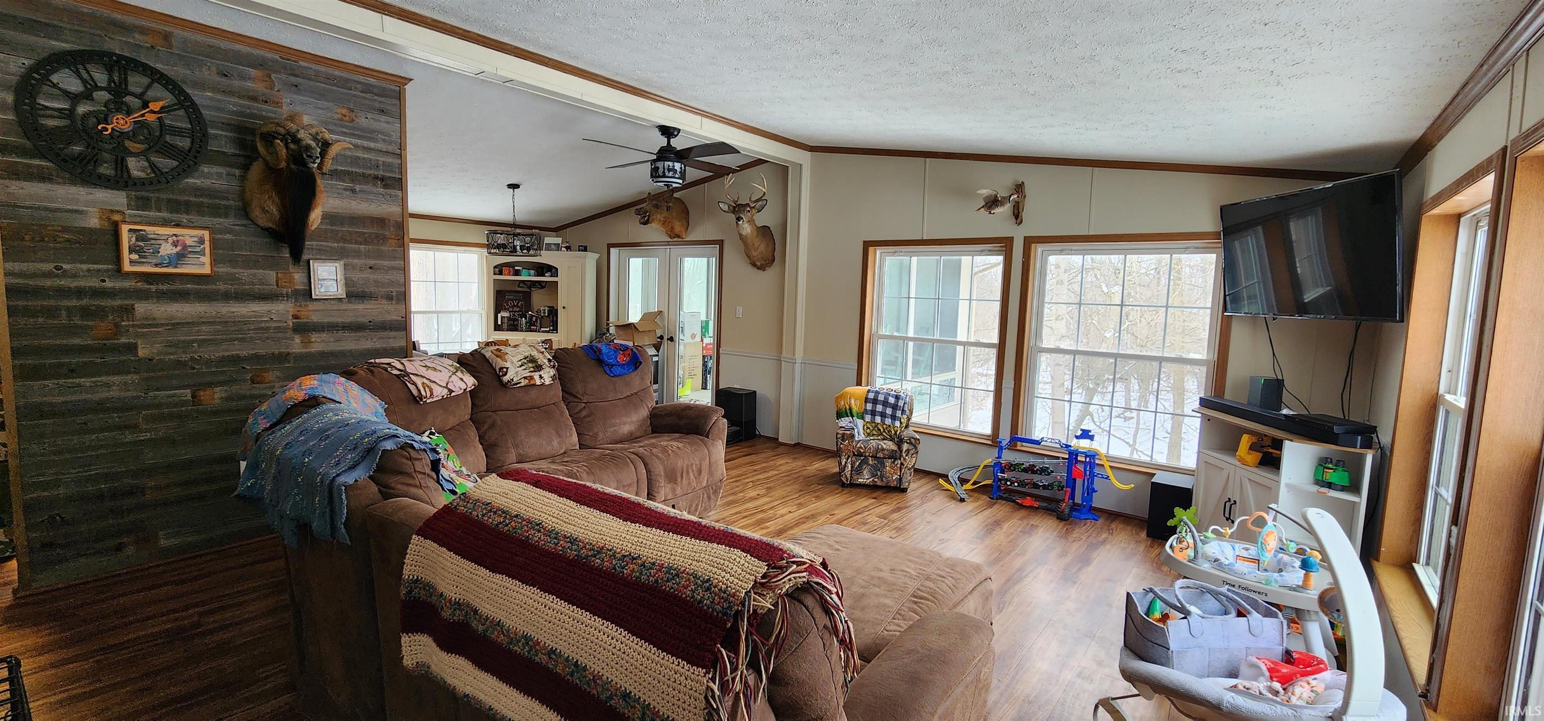 Living room featuring a ceiling fan, wood finished floors, and ornamental molding