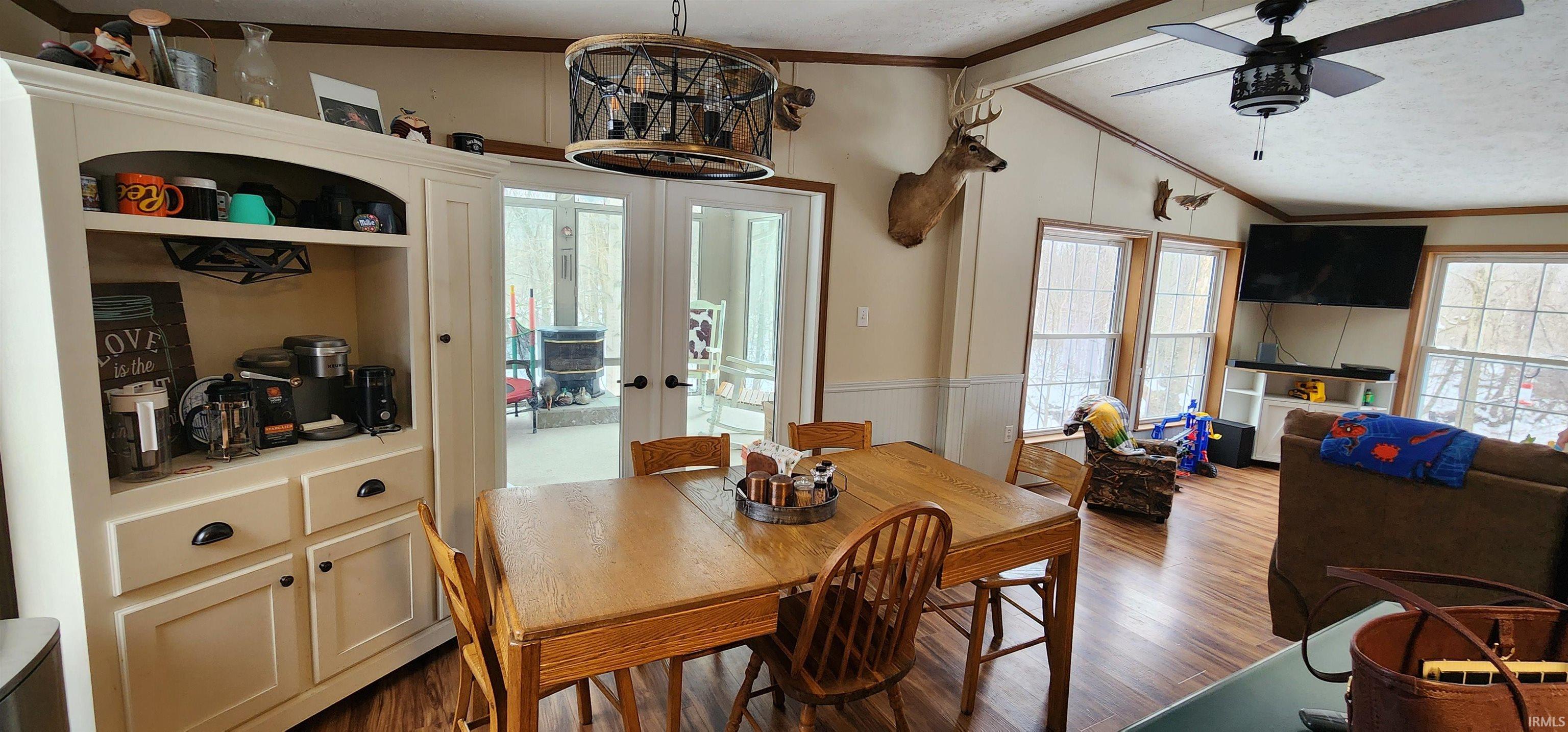Dining room with french doors, a ceiling fan, wood finished floors, beamed ceiling, and hanging lights