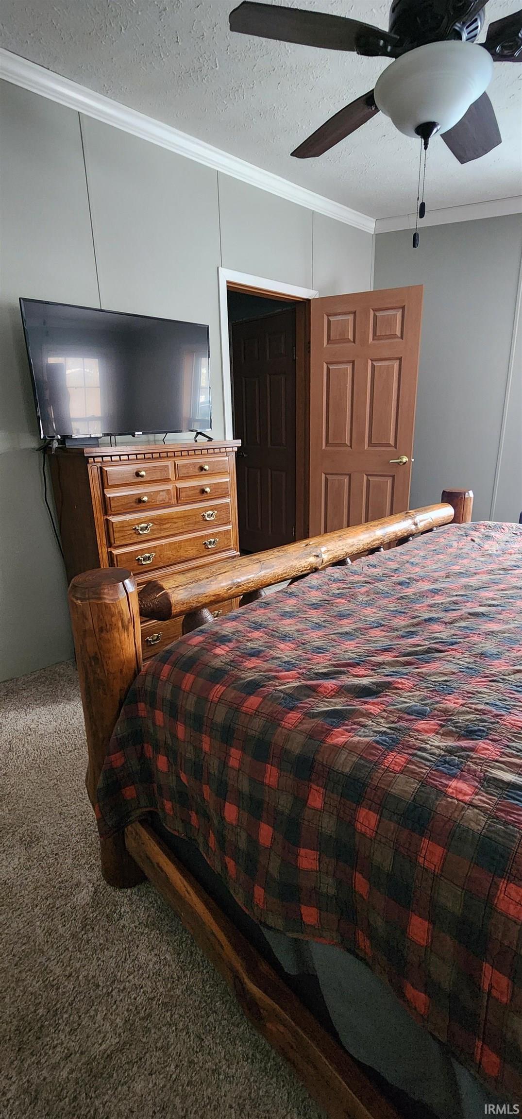 Carpeted bedroom with ornamental molding, a textured ceiling, and ceiling fan
