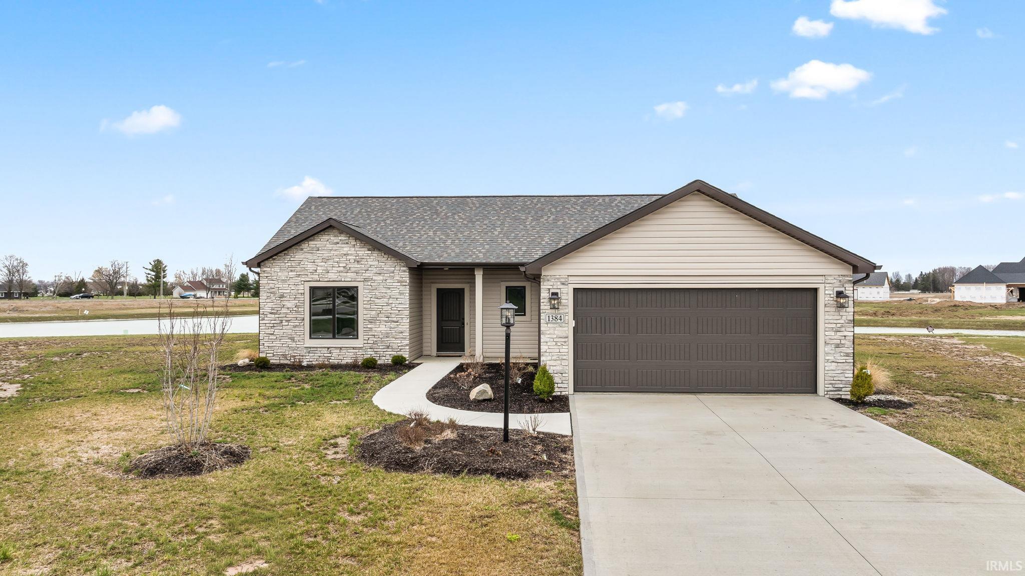 View of front of home featuring concrete driveway, a garage, stone siding, a front lawn, and roof with shingles