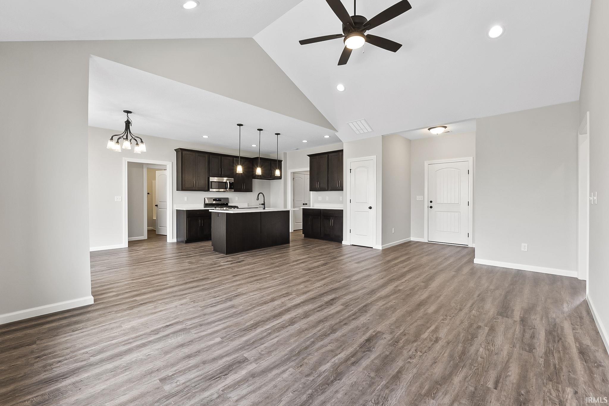 Unfurnished living room with ceiling fan, dark wood-style flooring, hanging lights, and a high ceiling