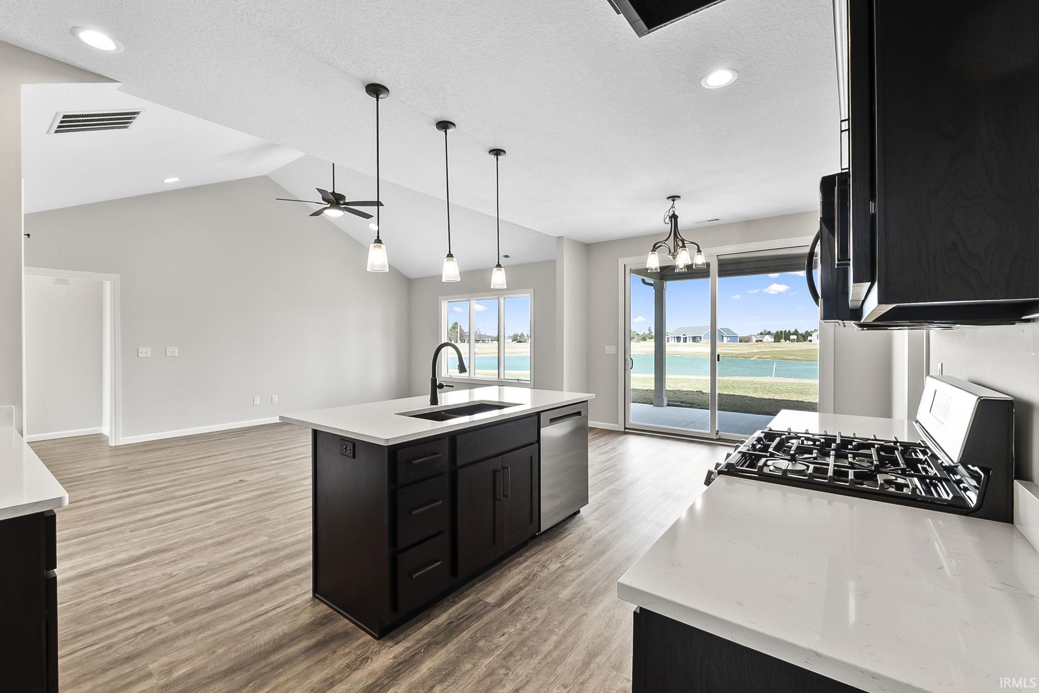 Kitchen featuring a chandelier, dark cabinets, a kitchen island with sink, and range with gas cooktop