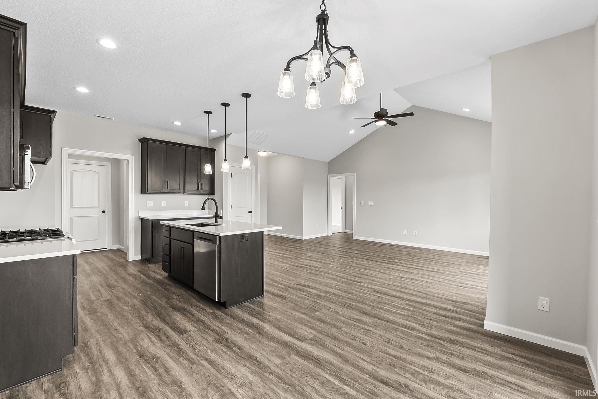 Kitchen with a kitchen island with sink, a ceiling fan, open floor plan, dark wood-style flooring, and a high ceiling
