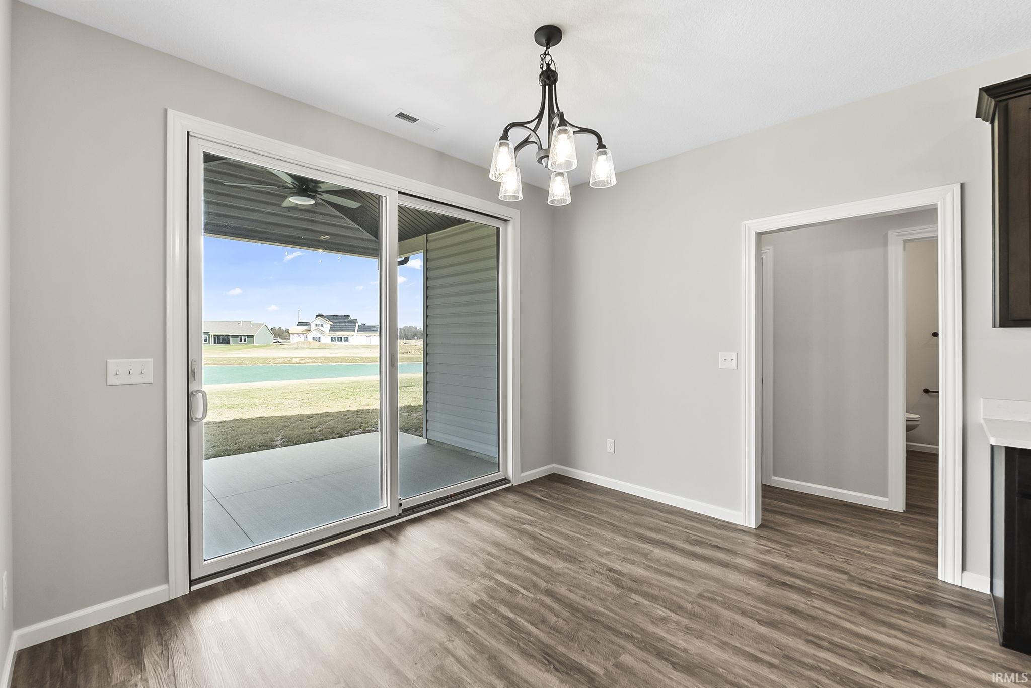 Unfurnished dining area with hanging lights, dark wood-style floors, and a ceiling fan