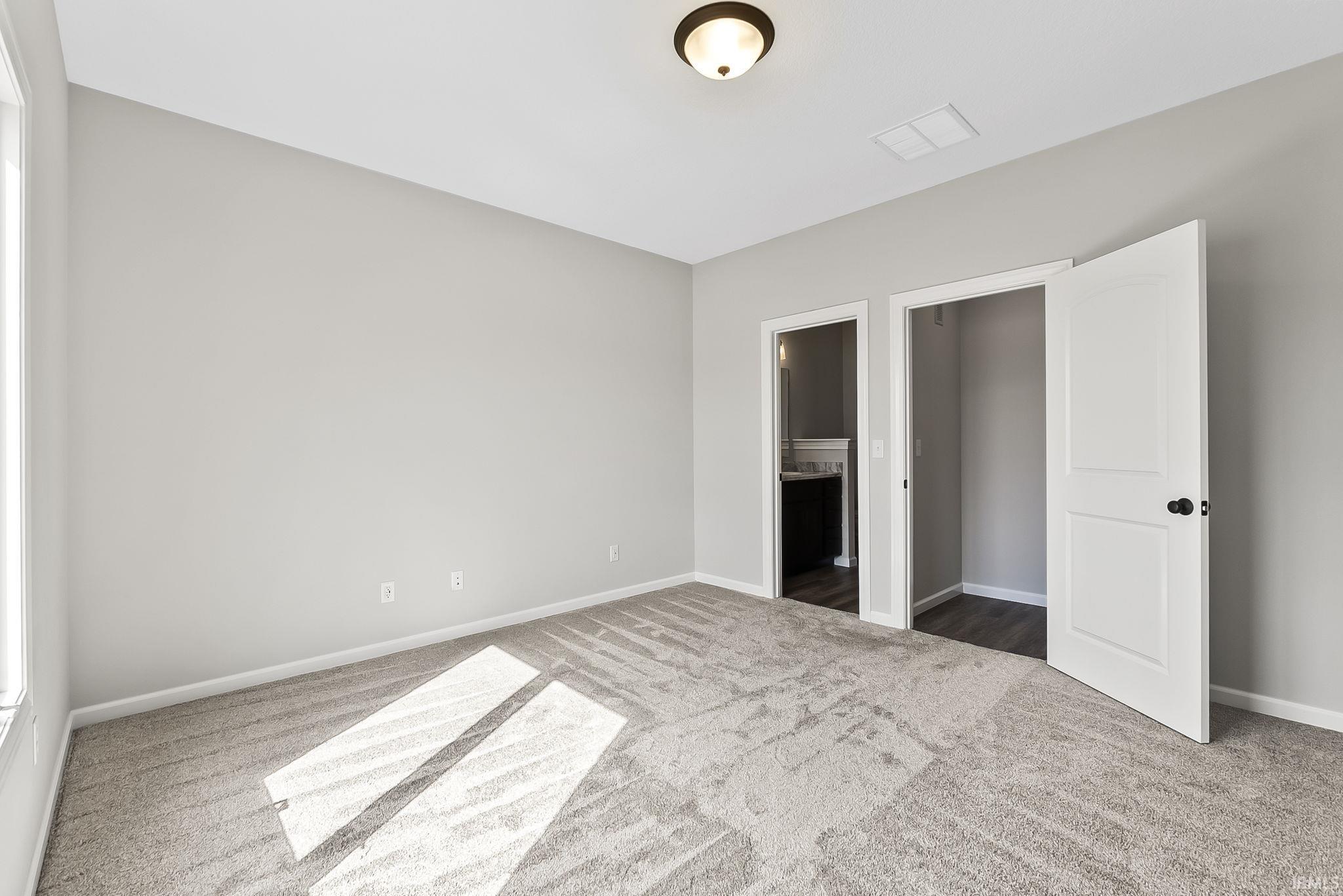 Unfurnished bedroom with dark colored carpet and connected bathroom