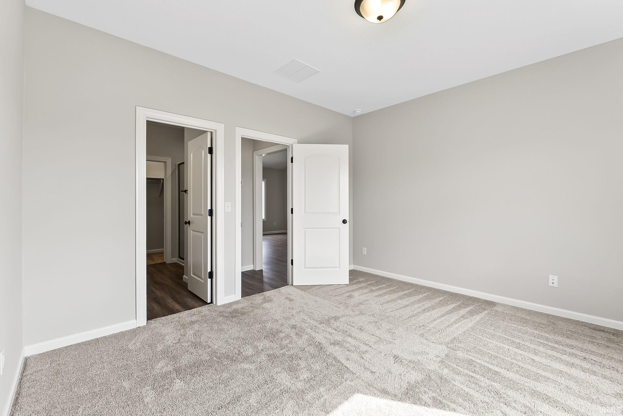 Unfurnished bedroom with dark carpet and baseboards