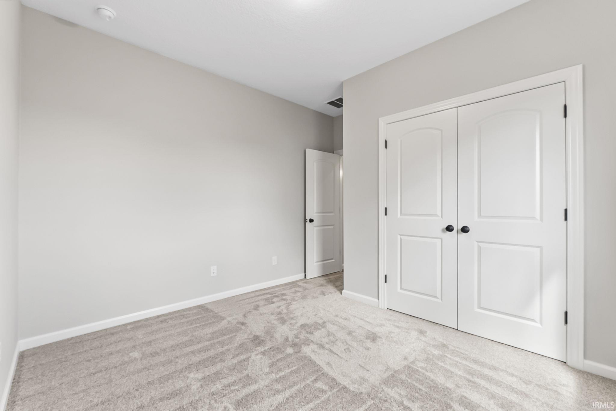 Unfurnished bedroom featuring light carpet and a closet