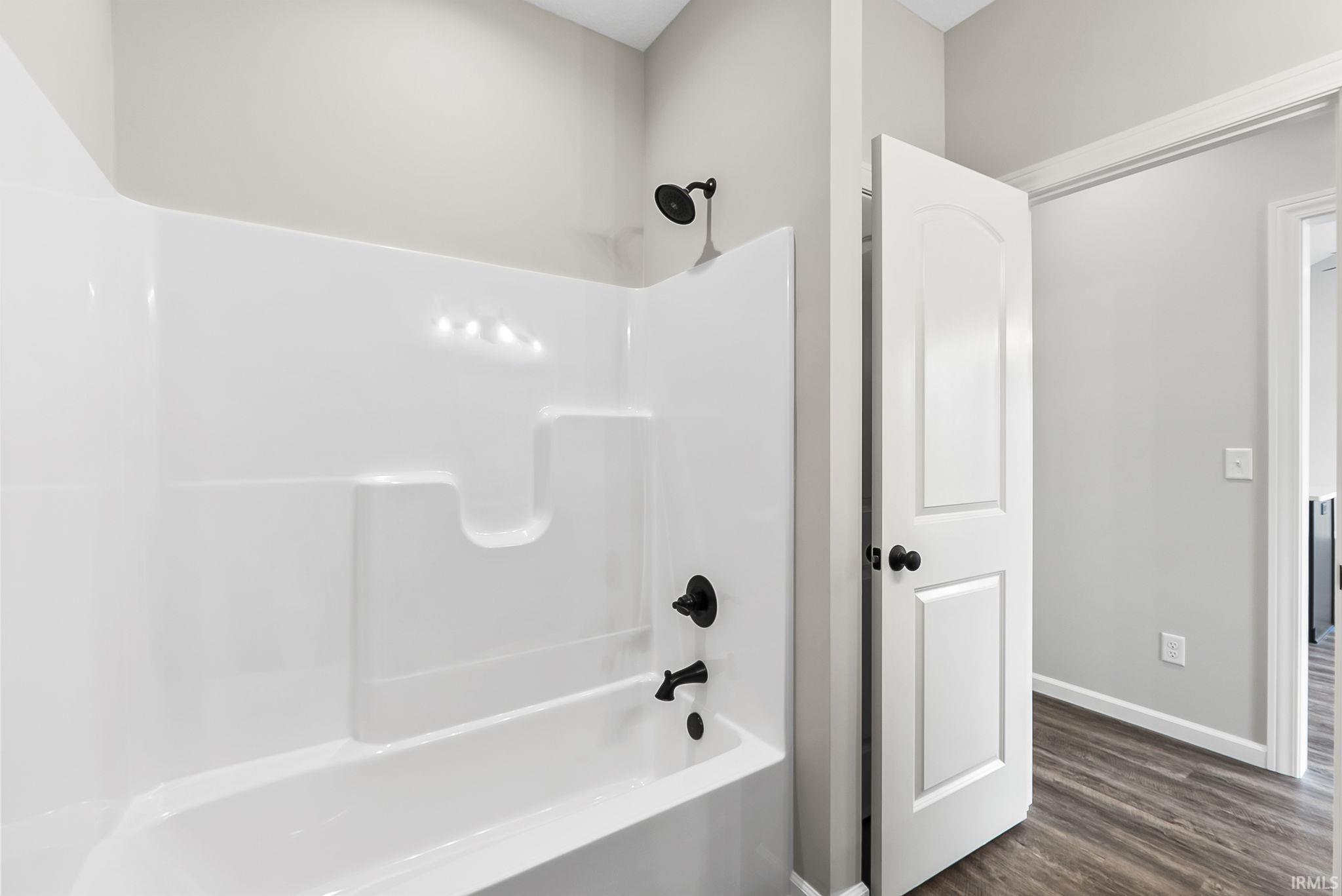 Bathroom with shower / washtub combination and dark wood-style floors