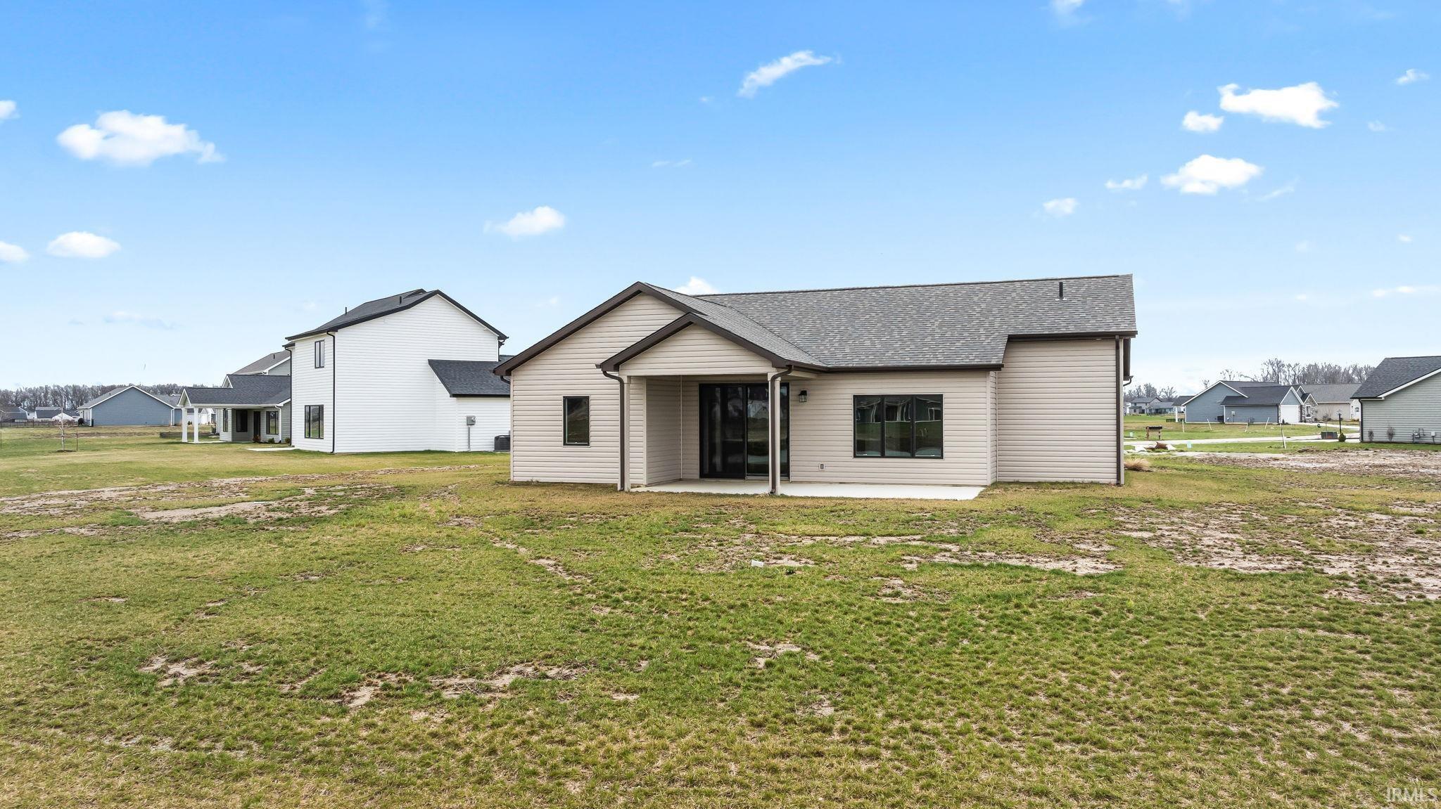 Rear view of house with a patio, a lawn, and roof with shingles