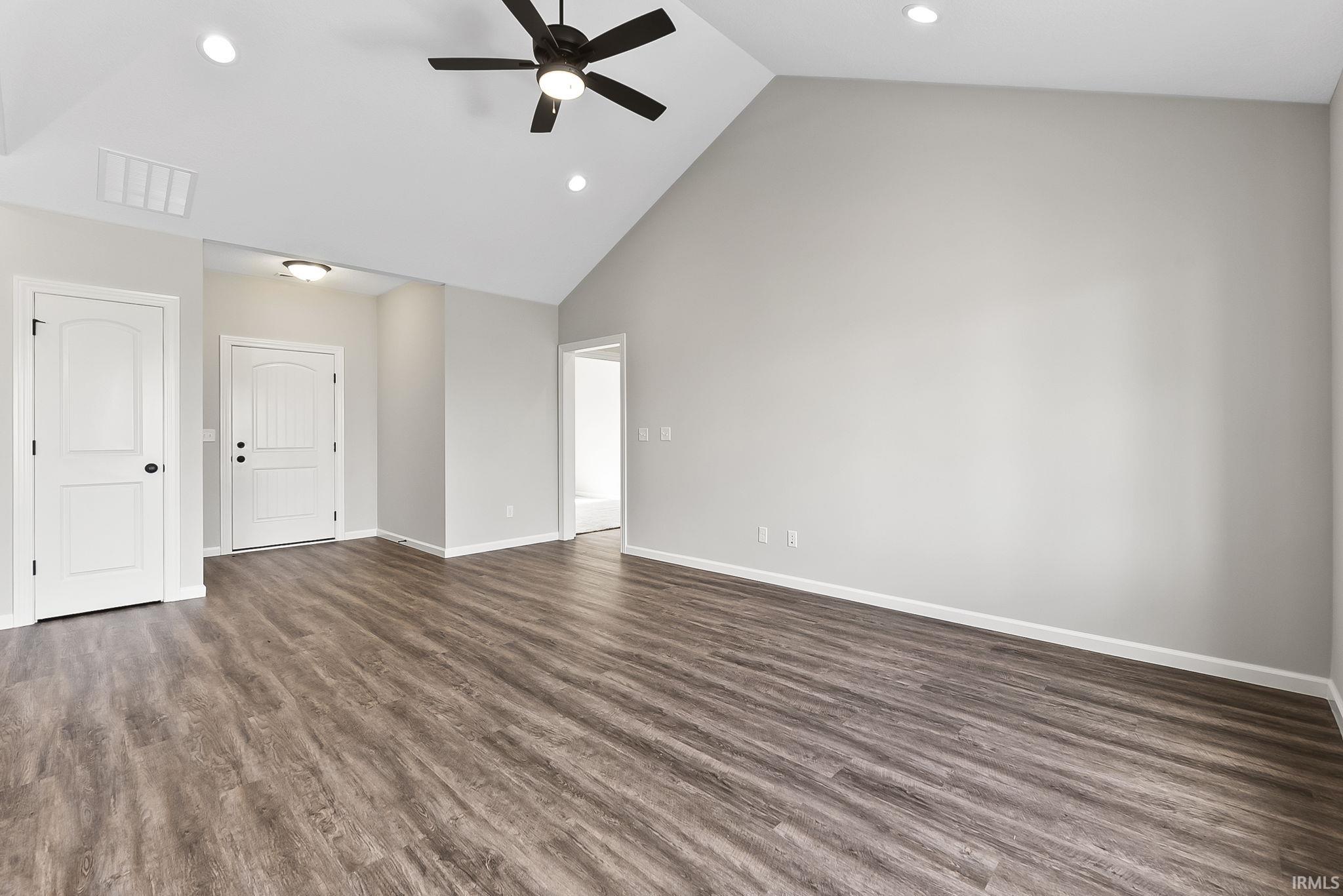 Empty room with a ceiling fan, dark wood finished floors, recessed lighting, and vaulted ceiling