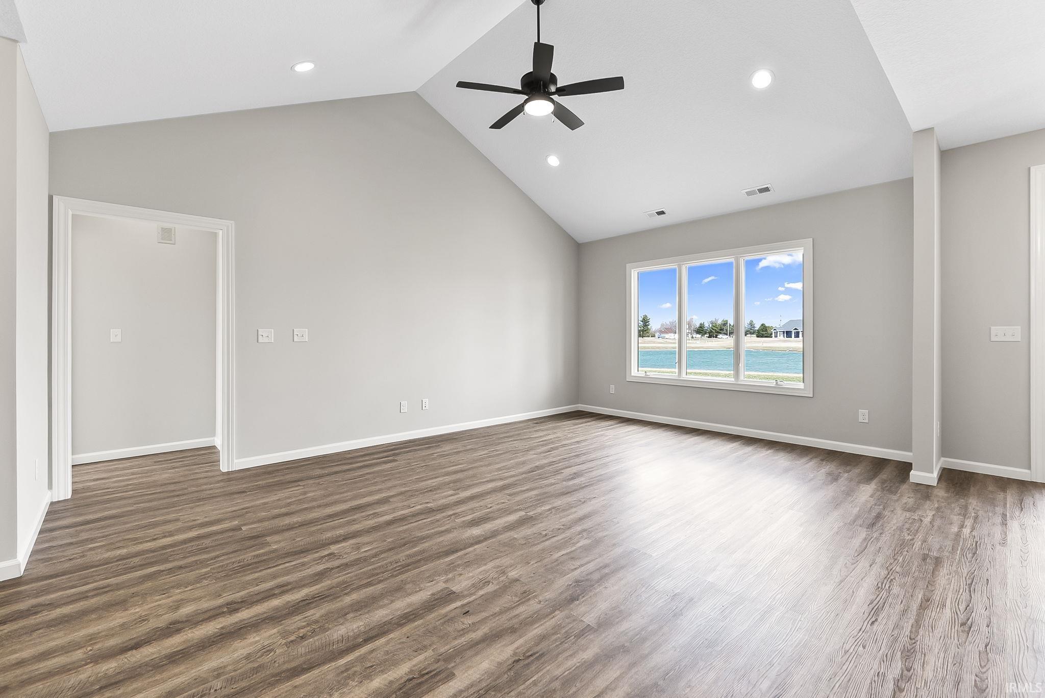 Empty room featuring a high ceiling, ceiling fan, recessed lighting, and dark wood-style floors