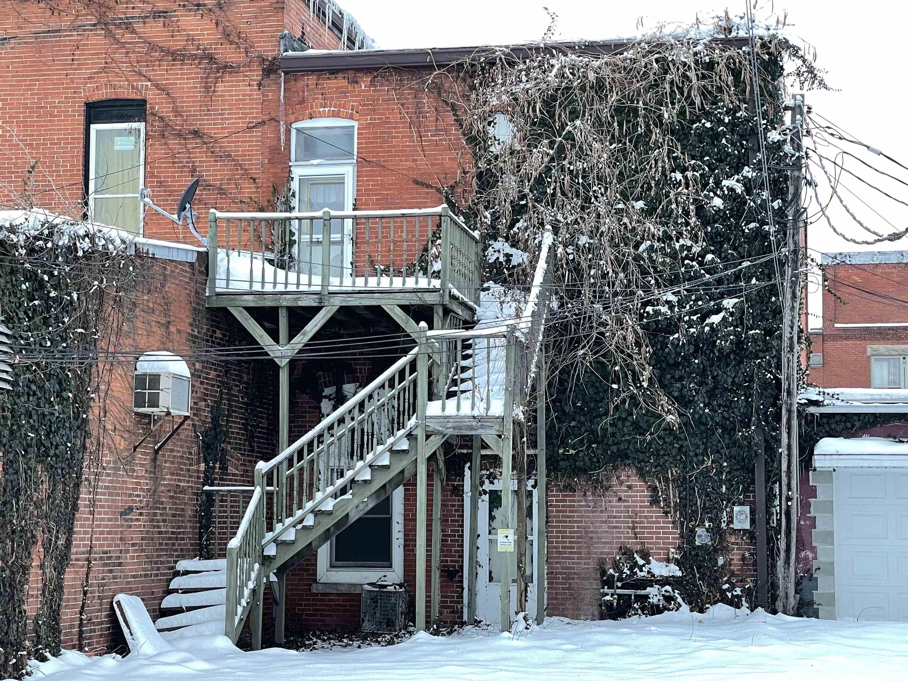 View of snowy exterior with brick siding and a central air condition unit