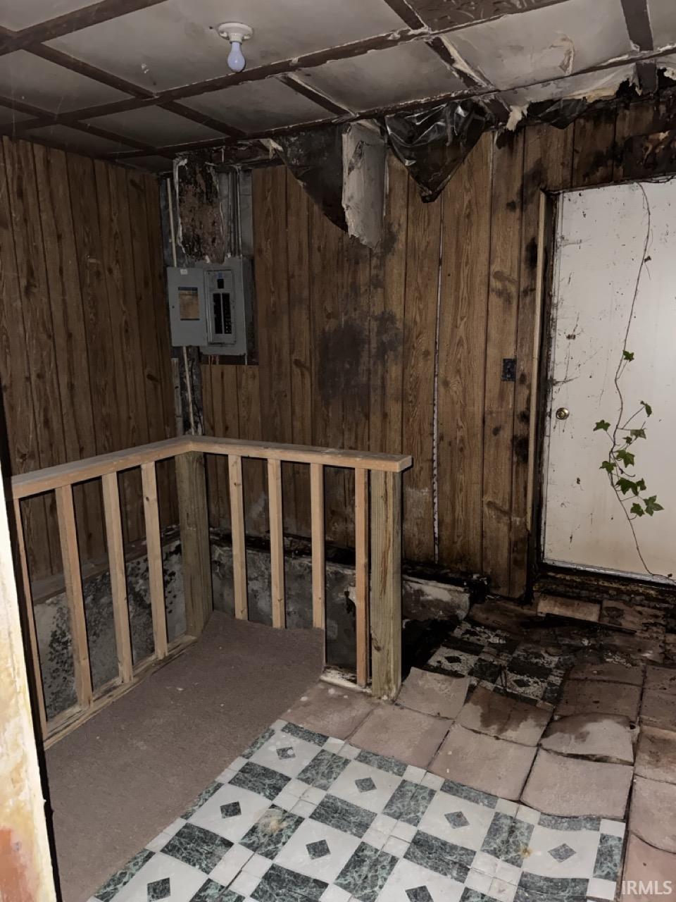 Unfinished basement with wood walls and electric panel