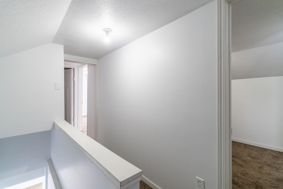 Corridor featuring carpet and an upstairs landing