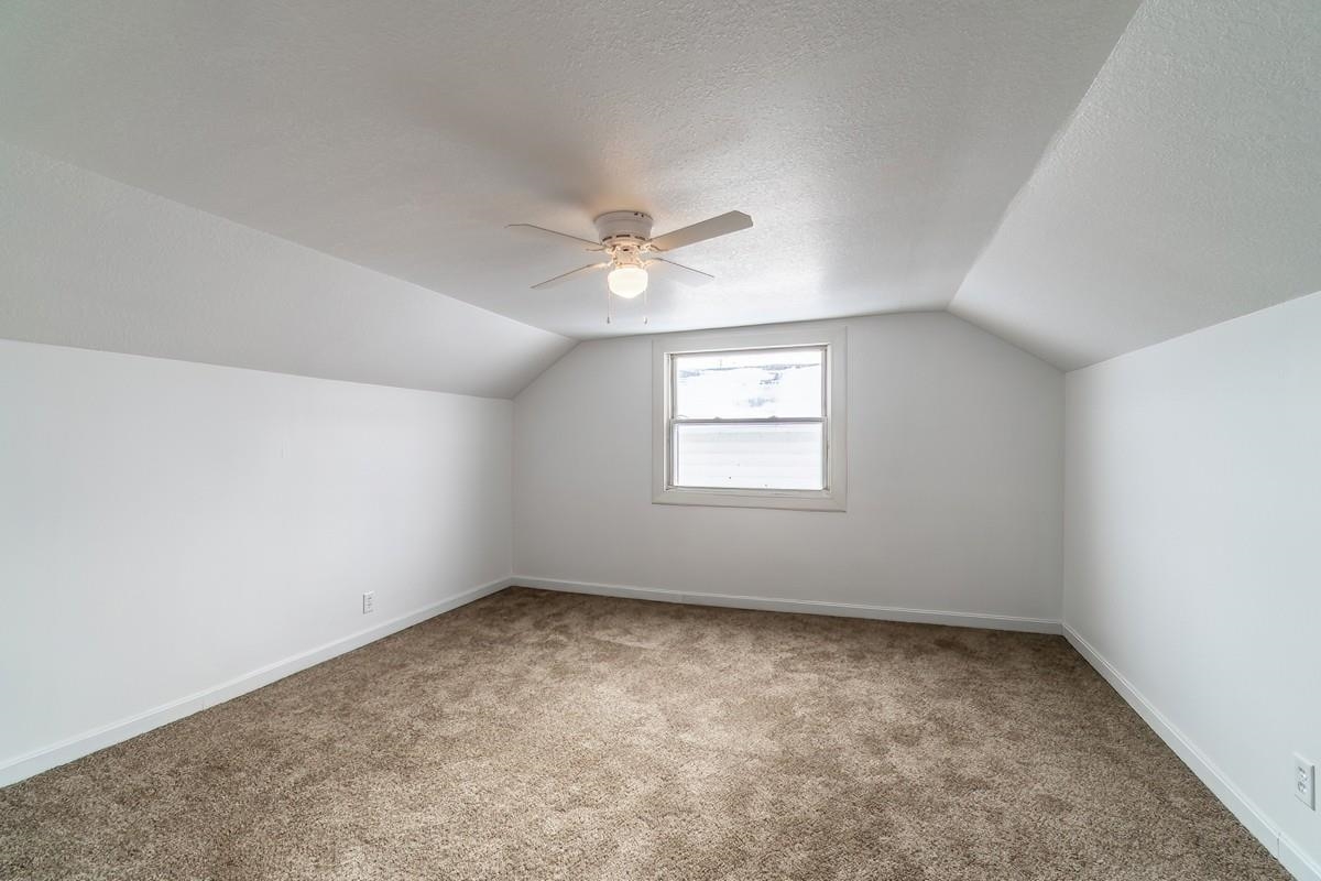 Bonus room with light carpet, a textured ceiling, and a ceiling fan