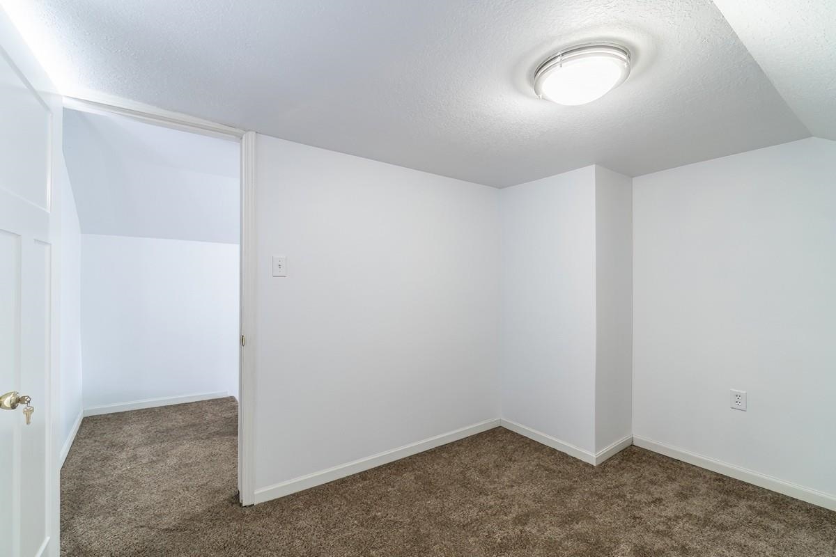 Empty room featuring dark colored carpet and baseboards