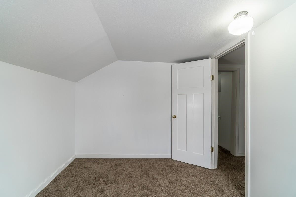 Additional living space featuring dark carpet and baseboards