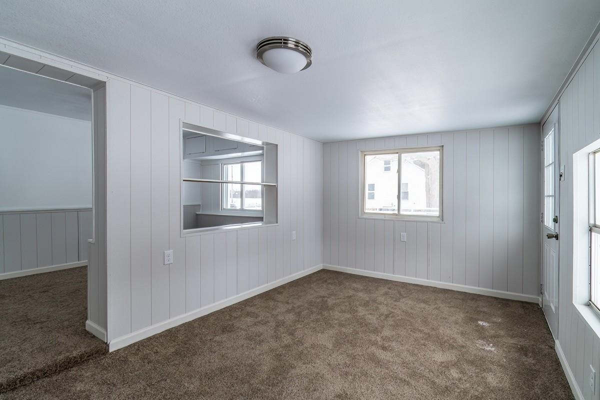 Empty room featuring dark carpet and wooden walls