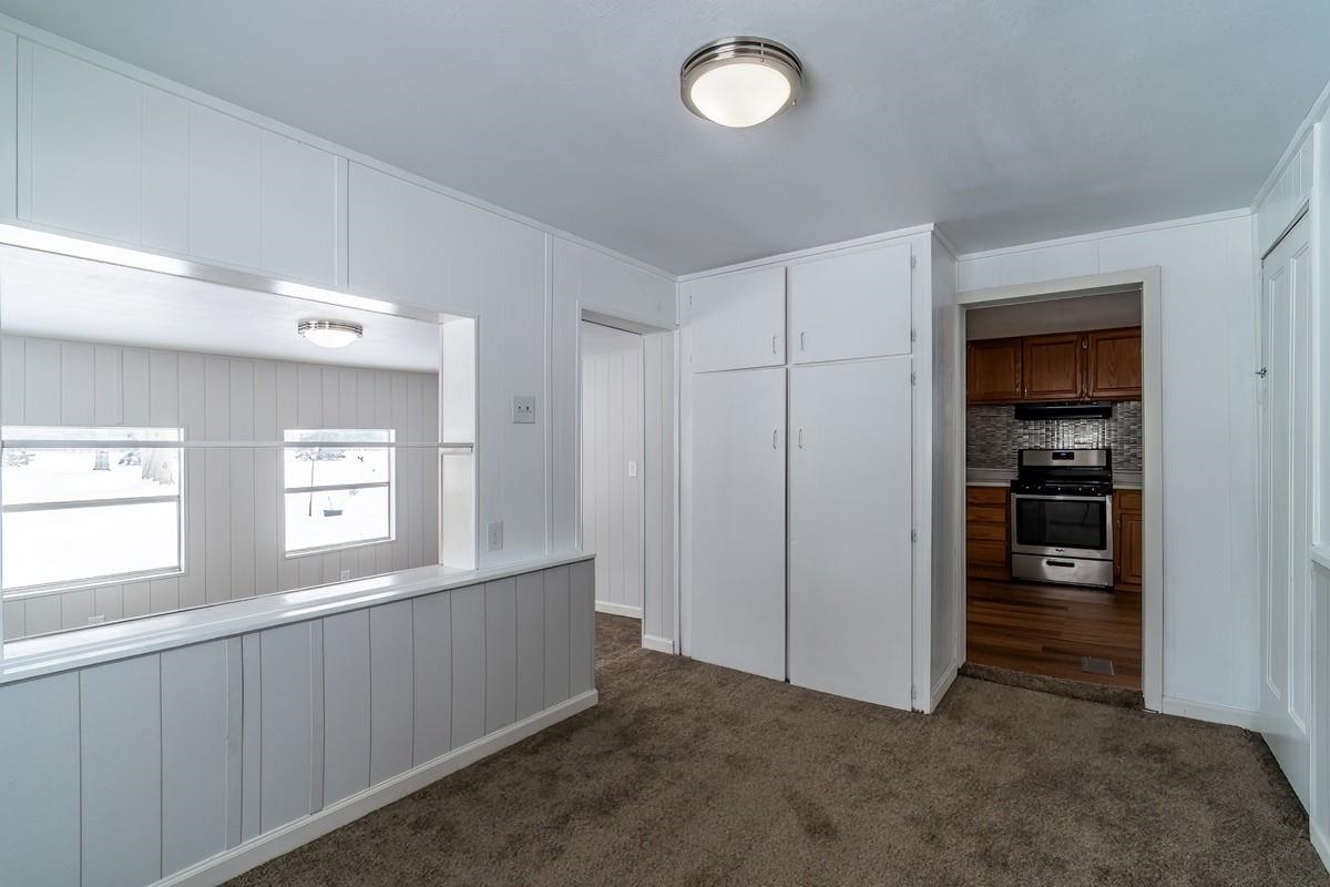 Kitchen featuring stainless steel stove, dark colored carpet, and tasteful backsplash