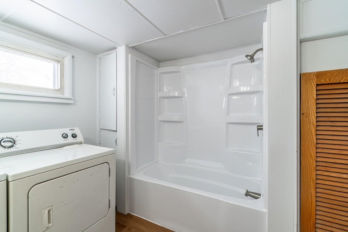 Bathroom with washer / clothes dryer,  shower combination, dark wood-style flooring, and a closet