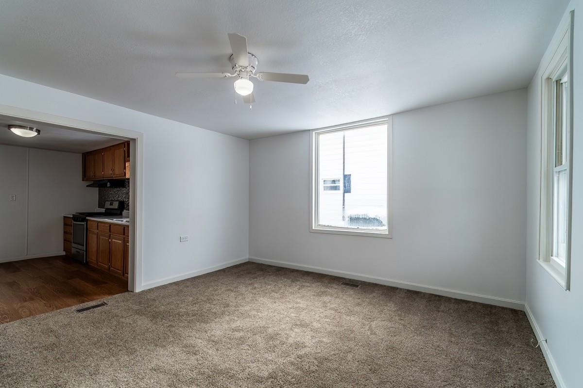 Unfurnished living room featuring dark colored carpet and ceiling fan