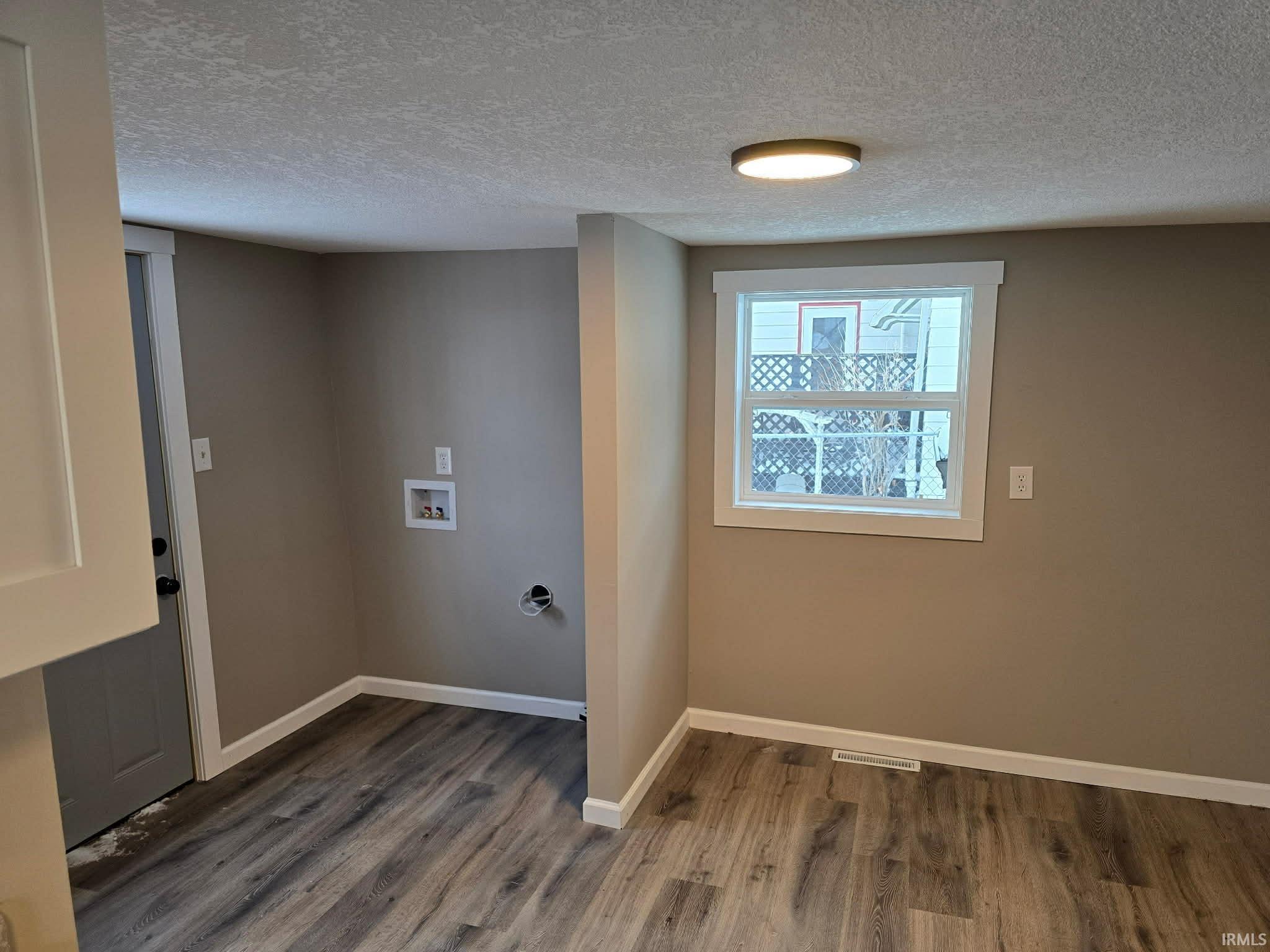 Laundry room featuring a textured ceiling, dark wood-style floors, and hookup for a washing machine