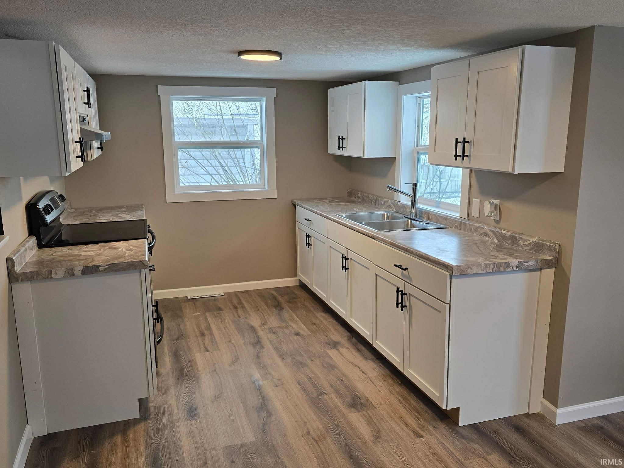 Kitchen featuring white cabinets, a textured ceiling, electric range, and dark wood-style flooring
