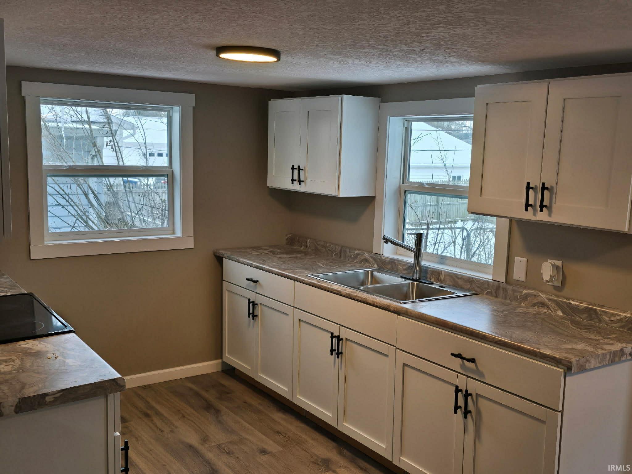 Kitchen featuring white cabinets, a textured ceiling, dark wood-style flooring, black electric range, and dark countertops