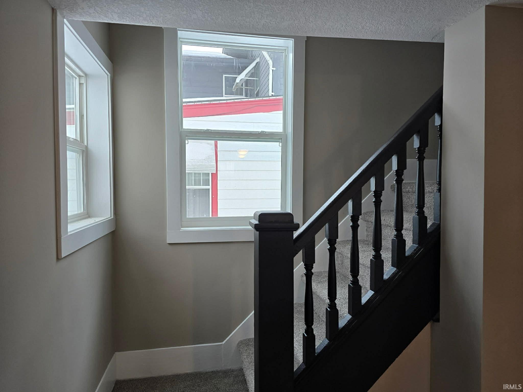 Stairs featuring baseboards and a textured ceiling