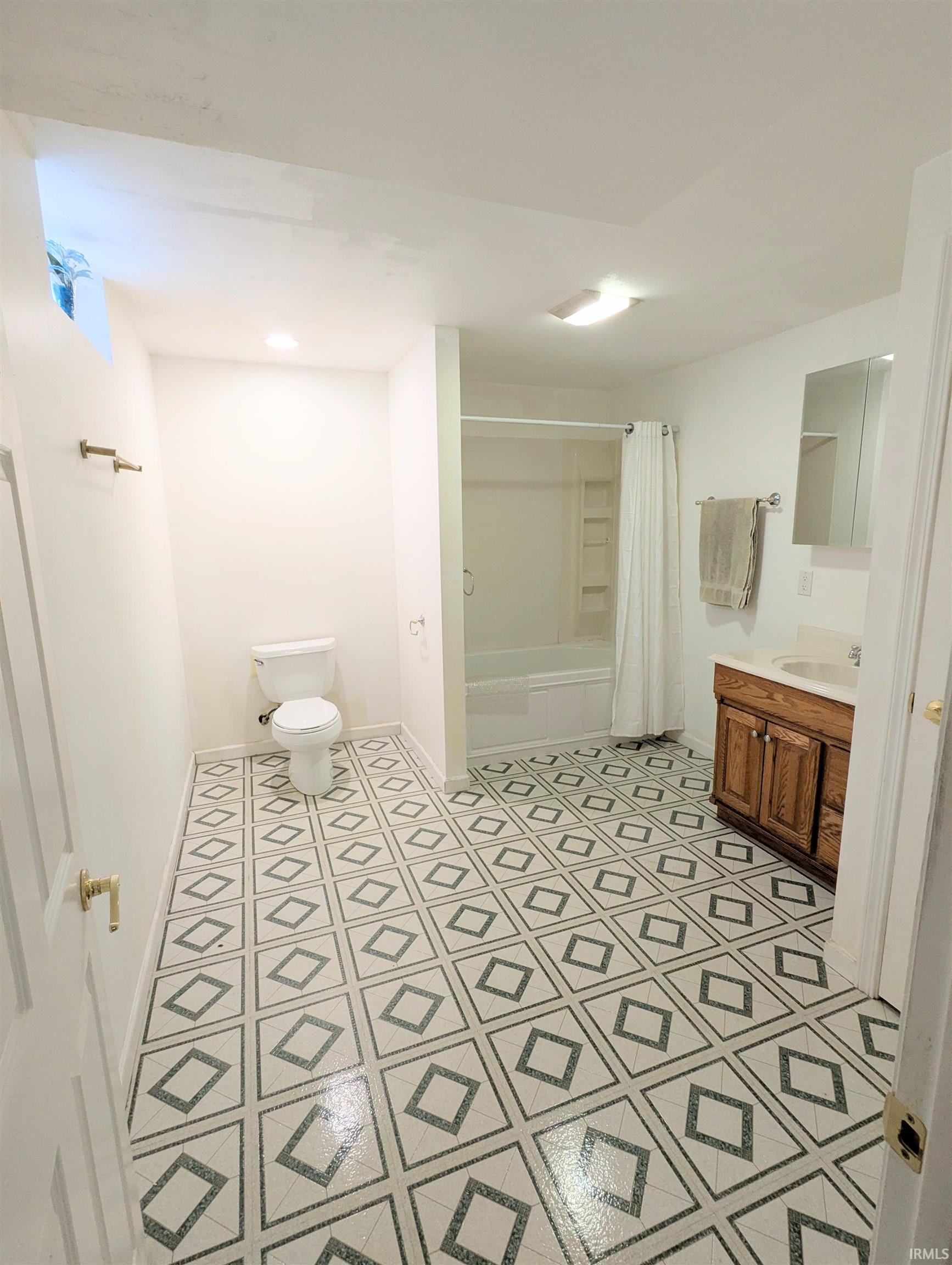 Basement Full bathroom with shower / bath combo with shower curtain, vanity, and recessed lighting