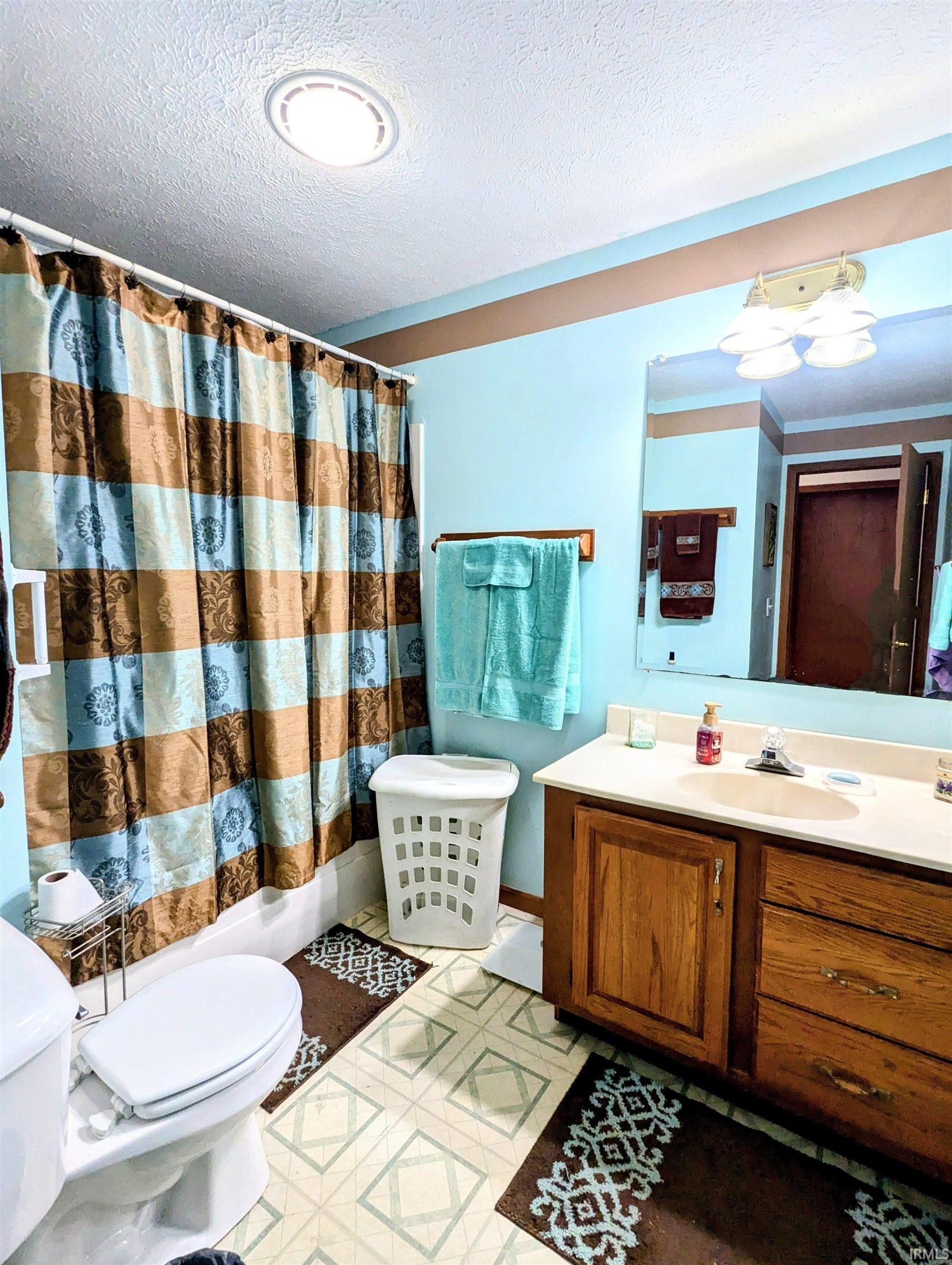 Full Bathroom with vanity, shower / bath combo with shower curtain, and a textured ceiling