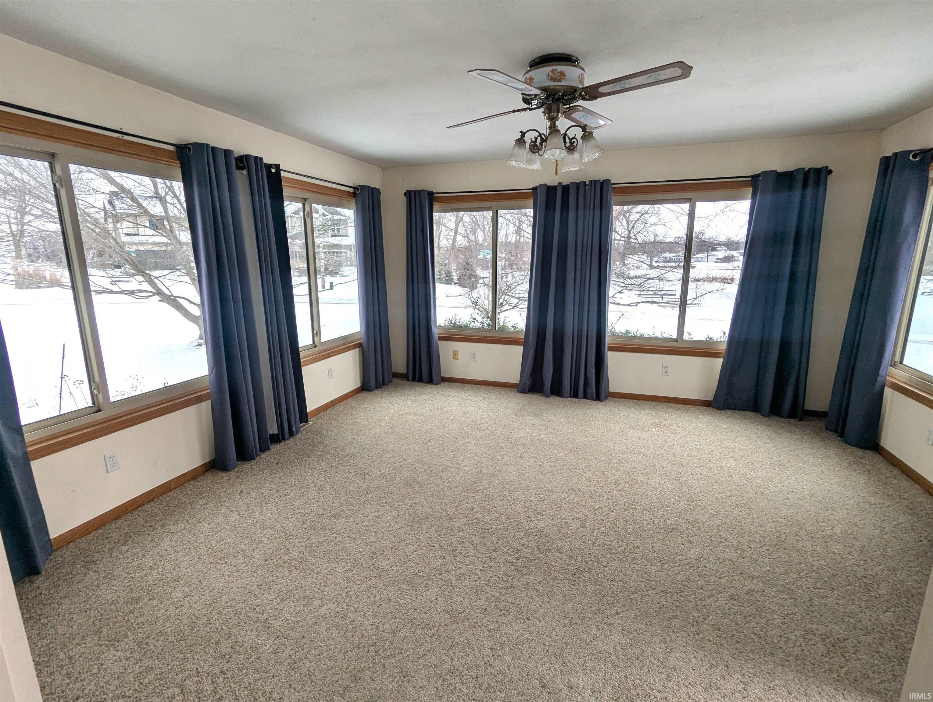 Wrap around windows room featuring light carpet and a ceiling fan