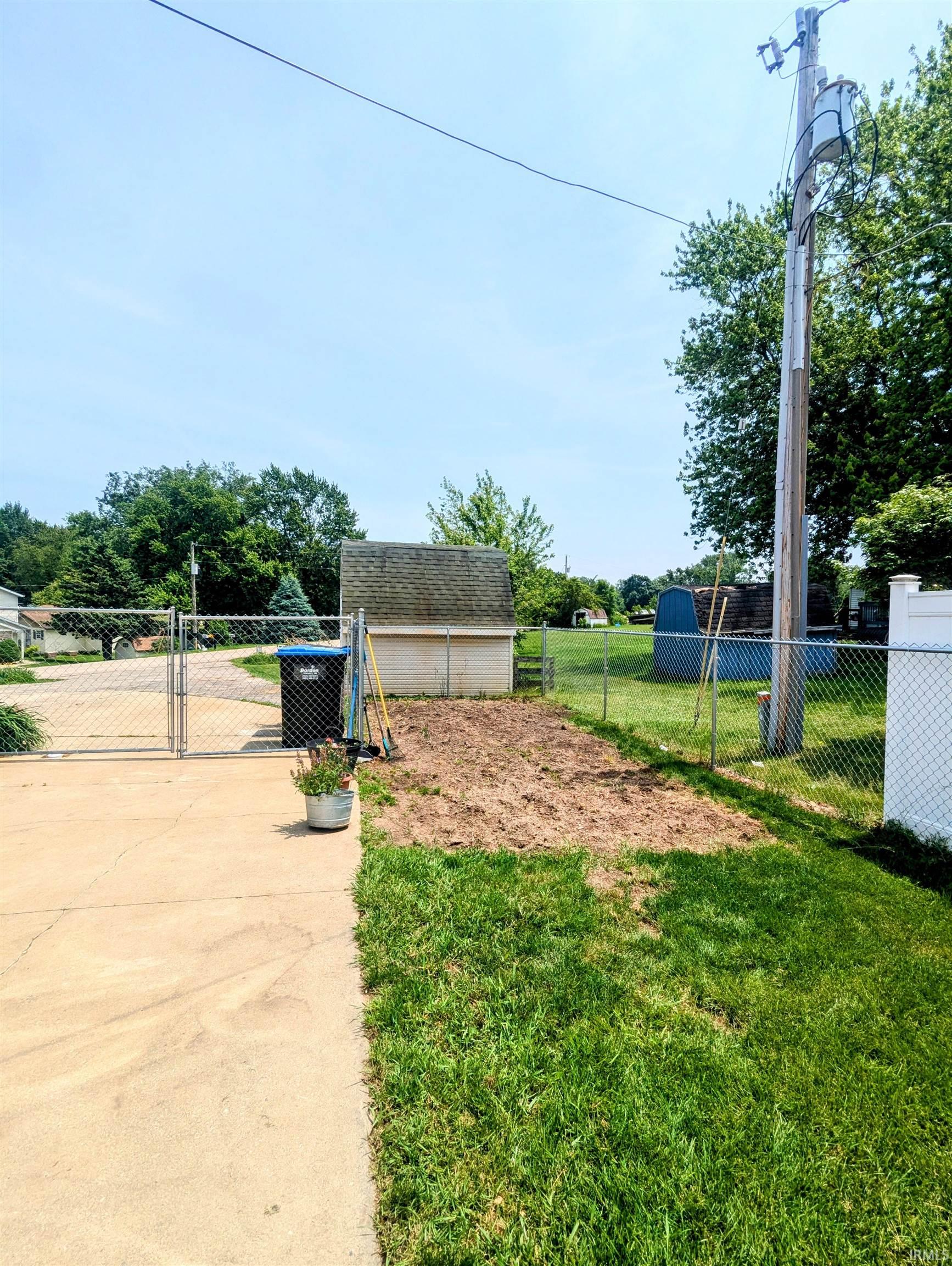 View of garden area with a gate and a shed