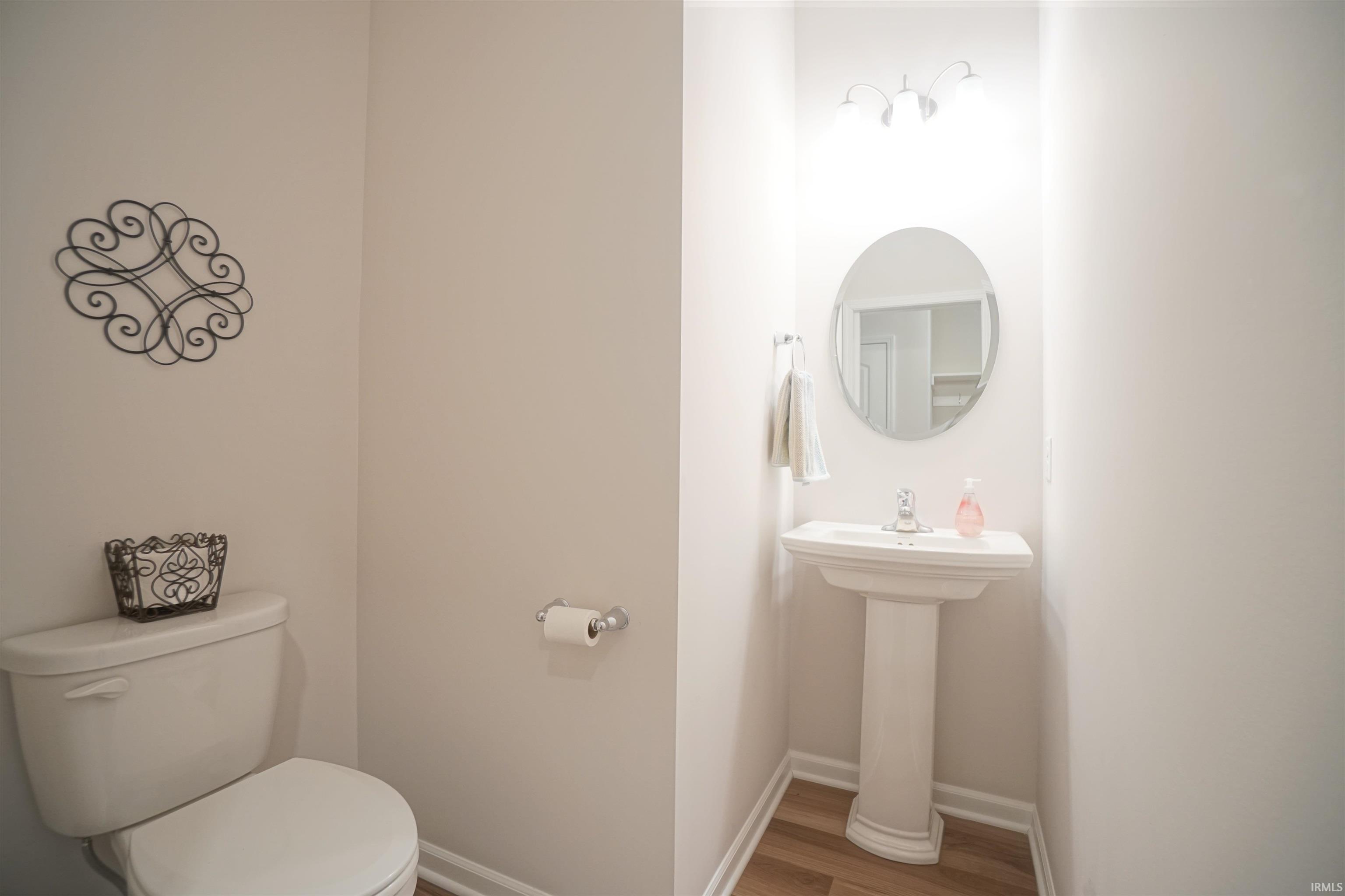 Half bathroom with toilet and wood finished floors