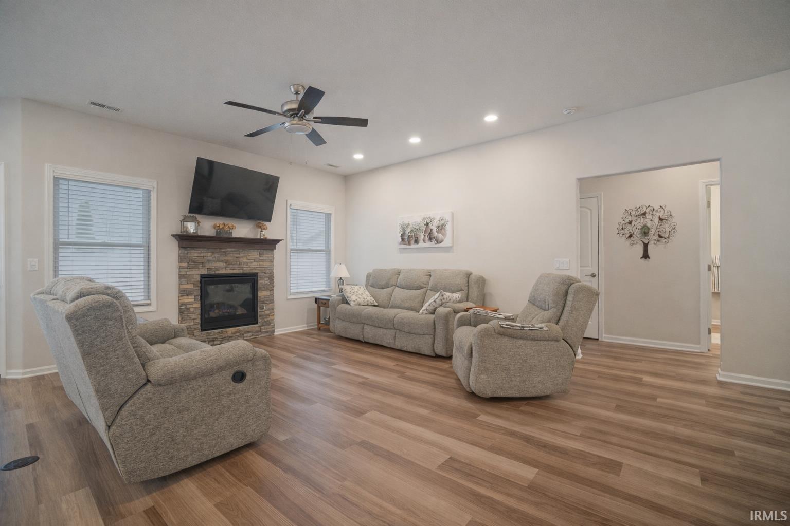 Living room with wood finished floors, a fireplace, recessed lighting, and a ceiling fan