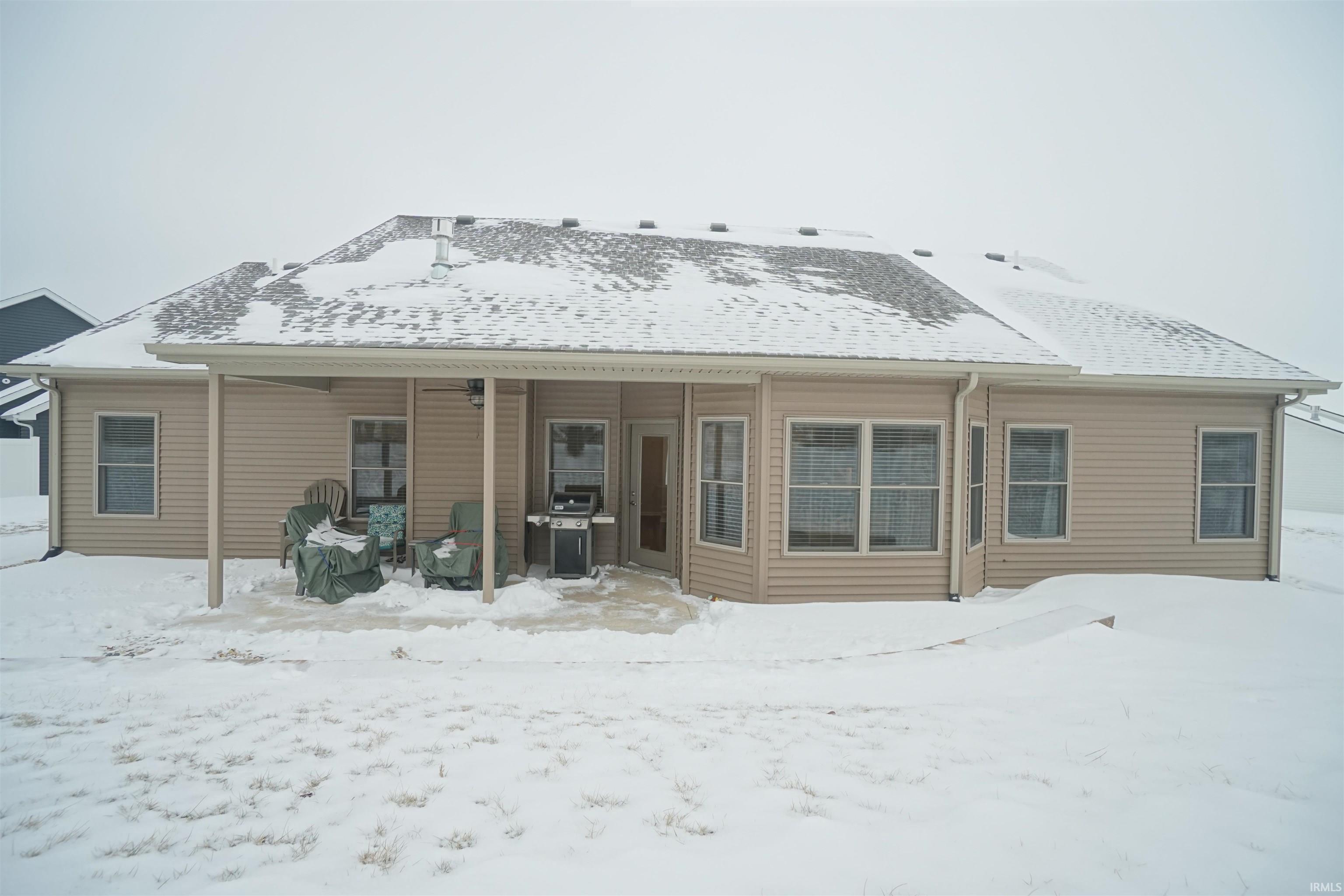 Snow covered rear of property featuring a patio