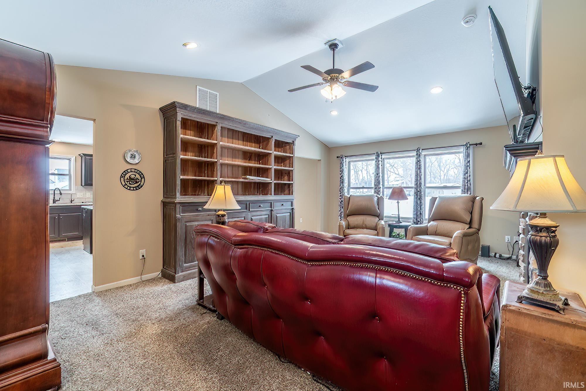 Living area with light colored carpet, a ceiling fan, and recessed lighting
