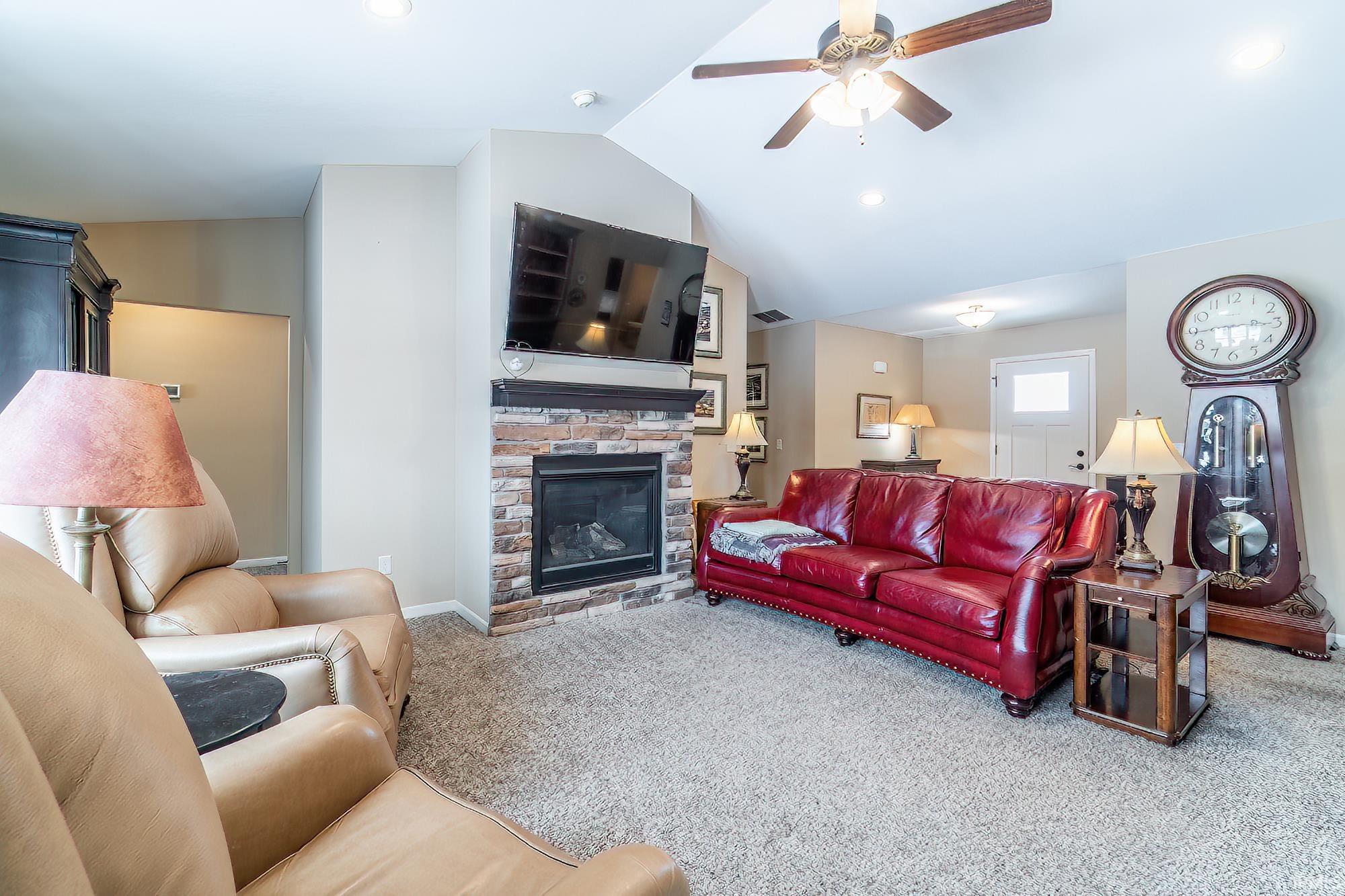 Carpeted living room with ceiling fan and a fireplace