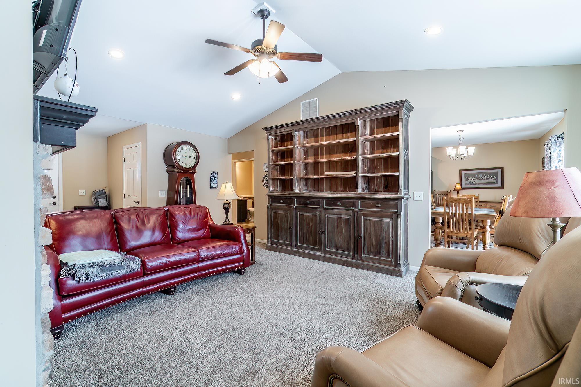 Living area featuring a ceiling fan, light carpet, and a chandelier