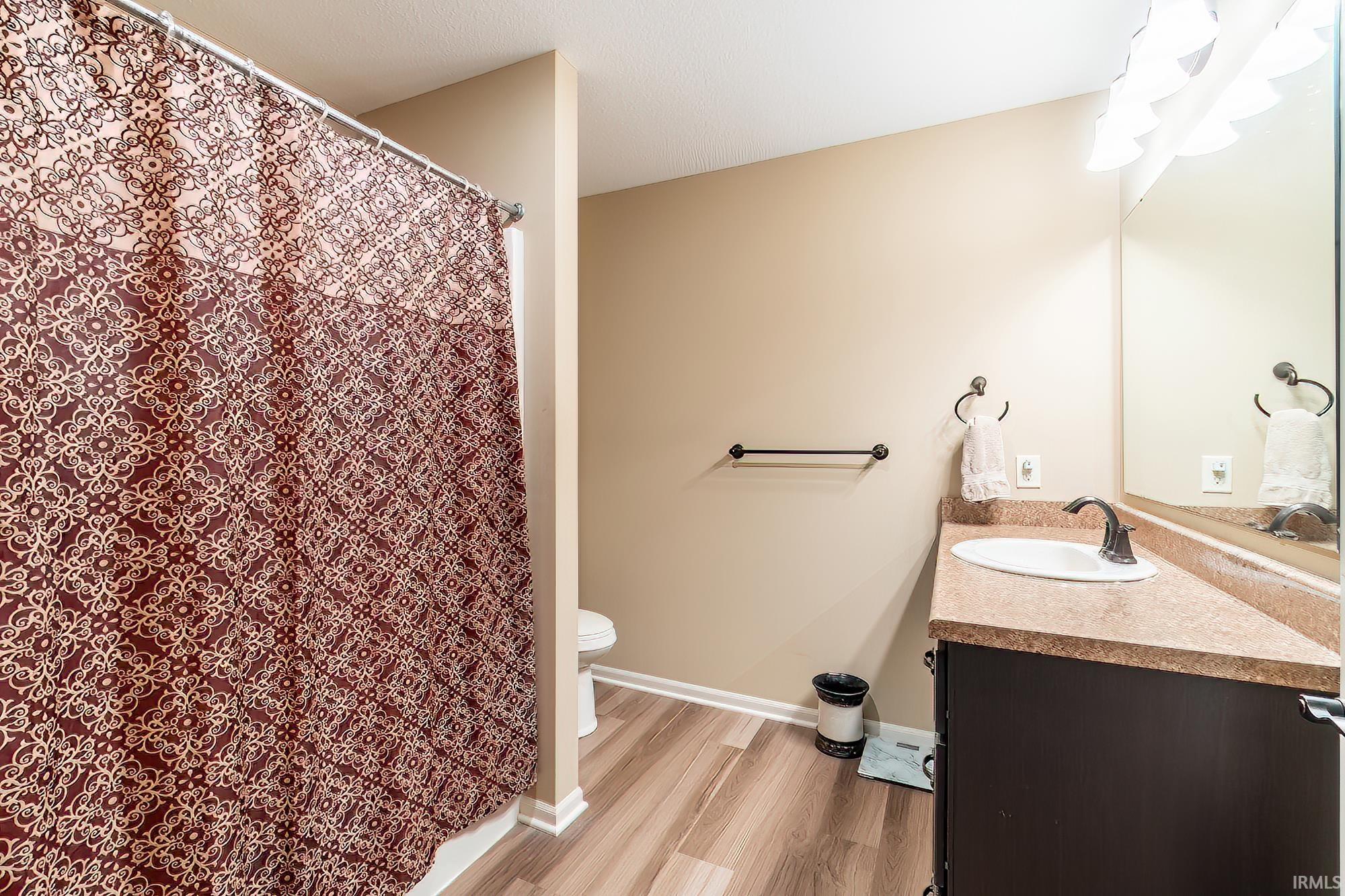 Full bathroom with a shower with shower curtain, vanity, and light wood finished floors